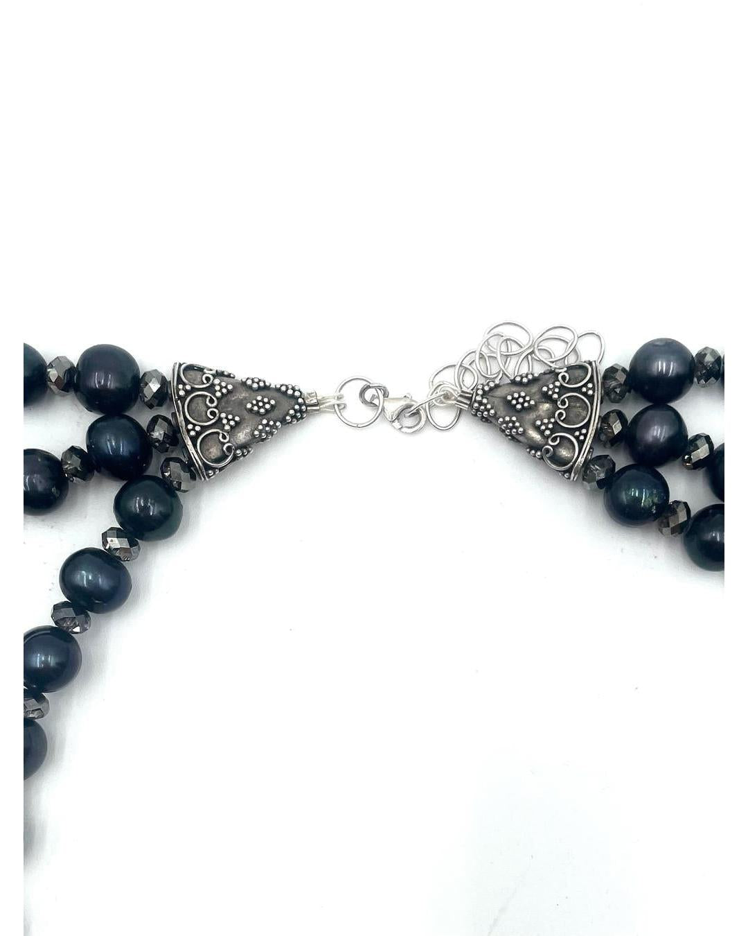 Triple strand necklace featuring black pearls and sparkling crystals with ornate silver filigree end caps and a lobster clasp.