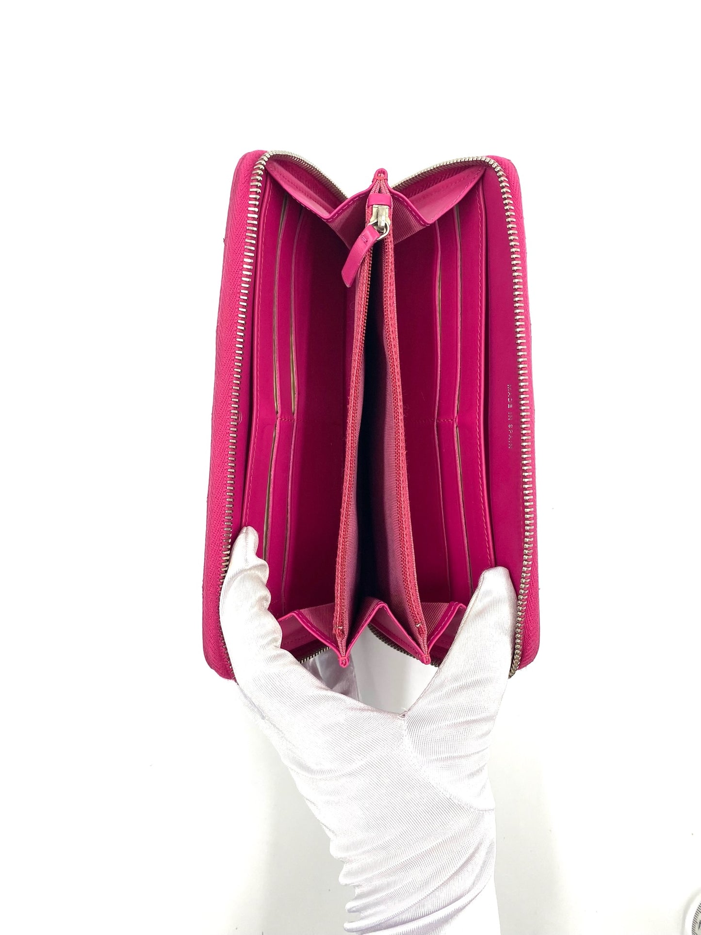 Chanel Pink Long Caviar Zip Wallet, open, held by a gloved hand, showing interior compartments.