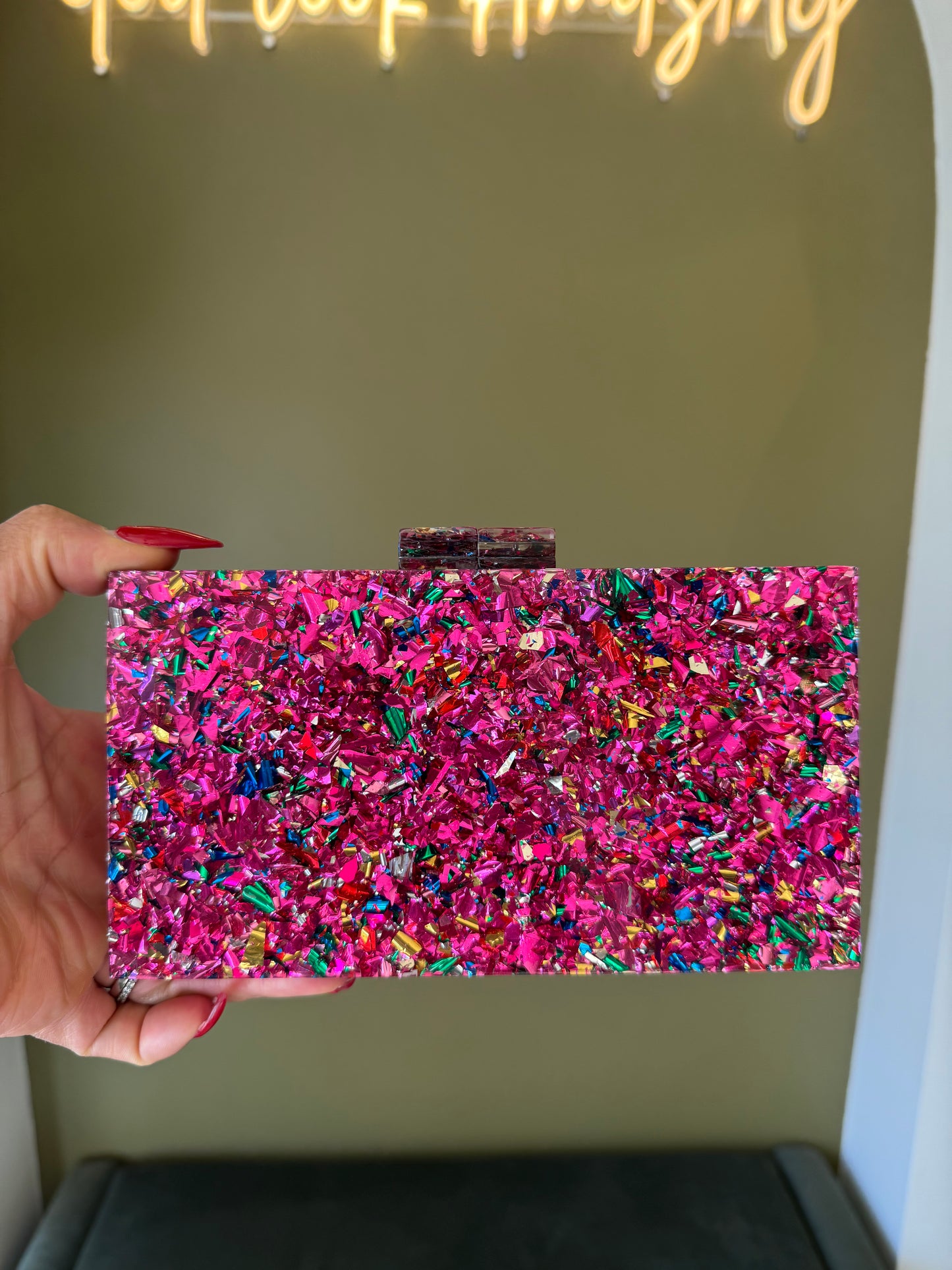 Rectangular pink acrylic clutch filled with vibrant multi-colored glitter confetti and a secure top clasp closure.