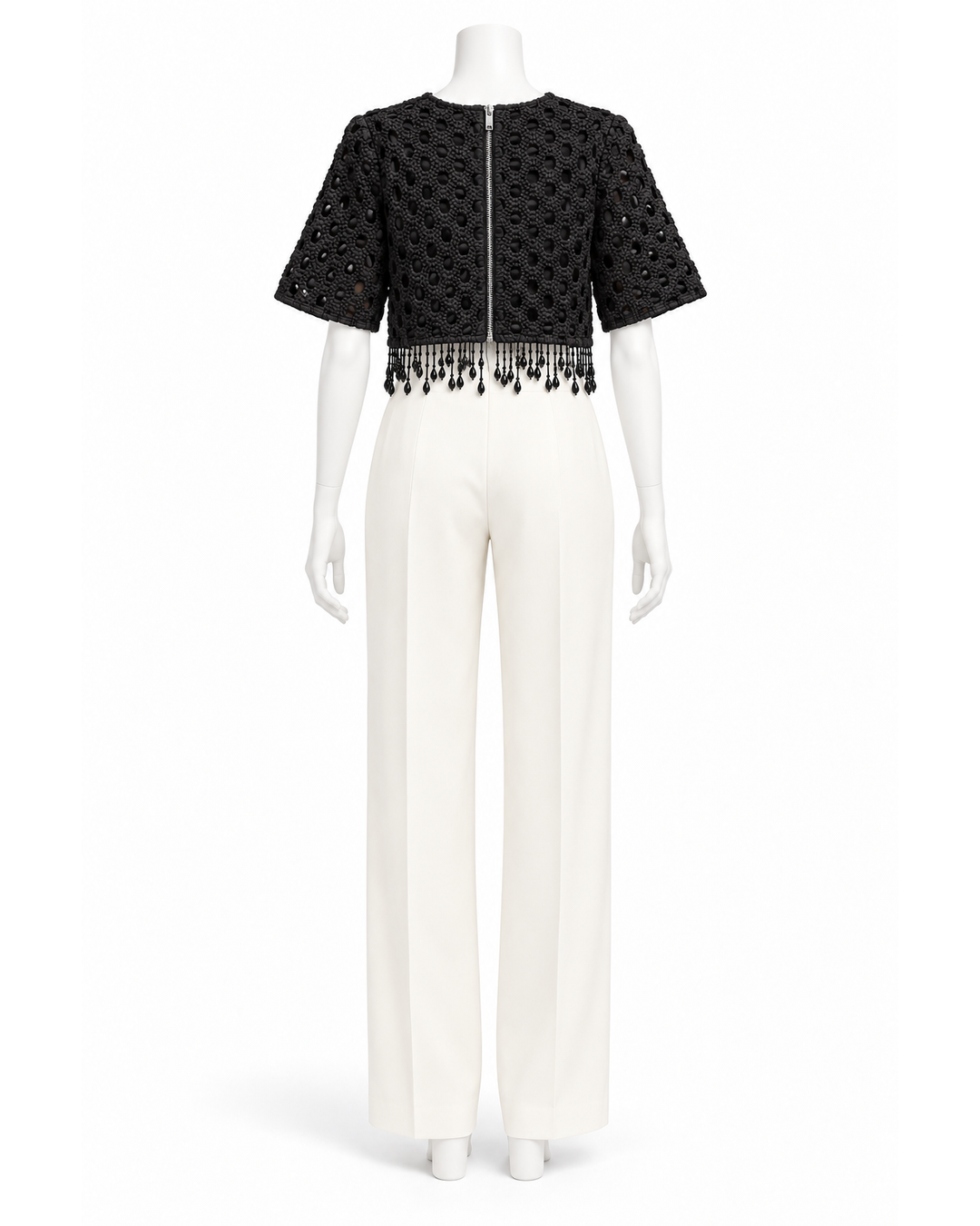 Ganni black short-sleeve crop top with textured crochet pattern, back zip closure, and beaded fringe hem.