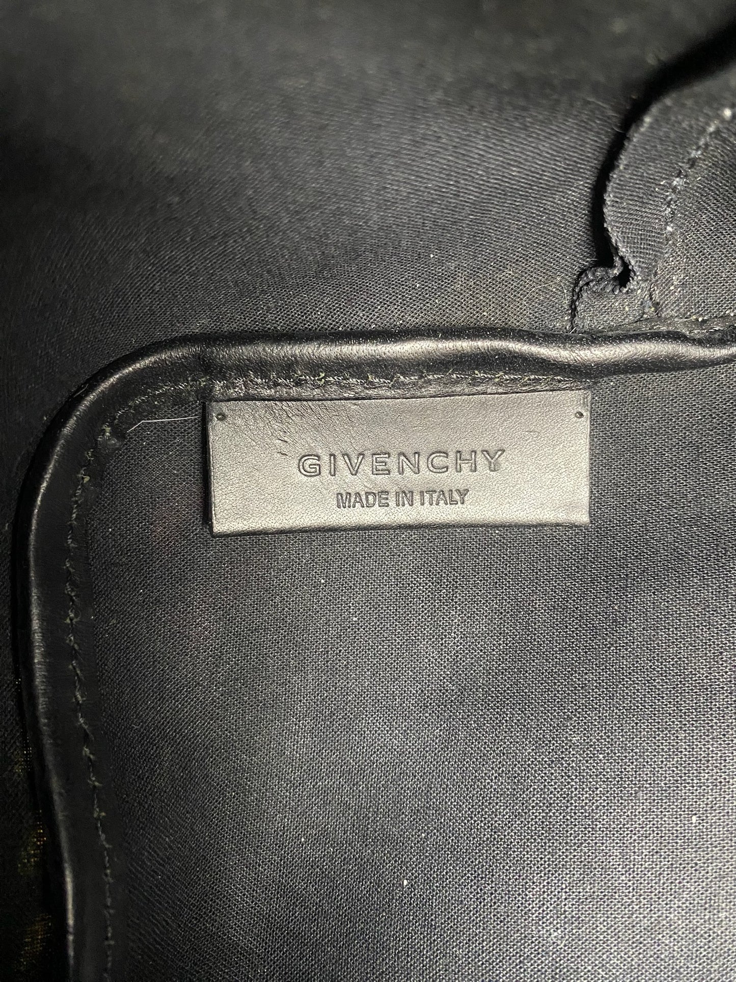 Givenchy "Made in Italy" black leather label stitched onto a black fabric lining.