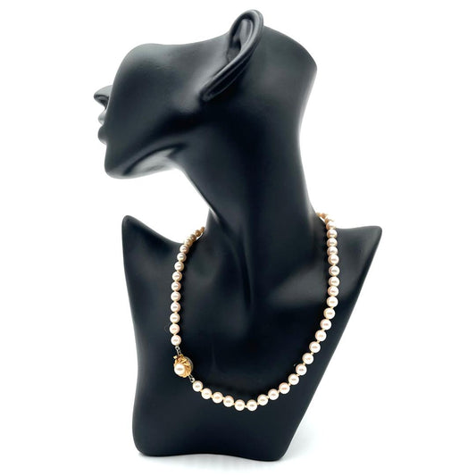 Majorica pearl necklace with a gold clasp, displayed on a black mannequin.