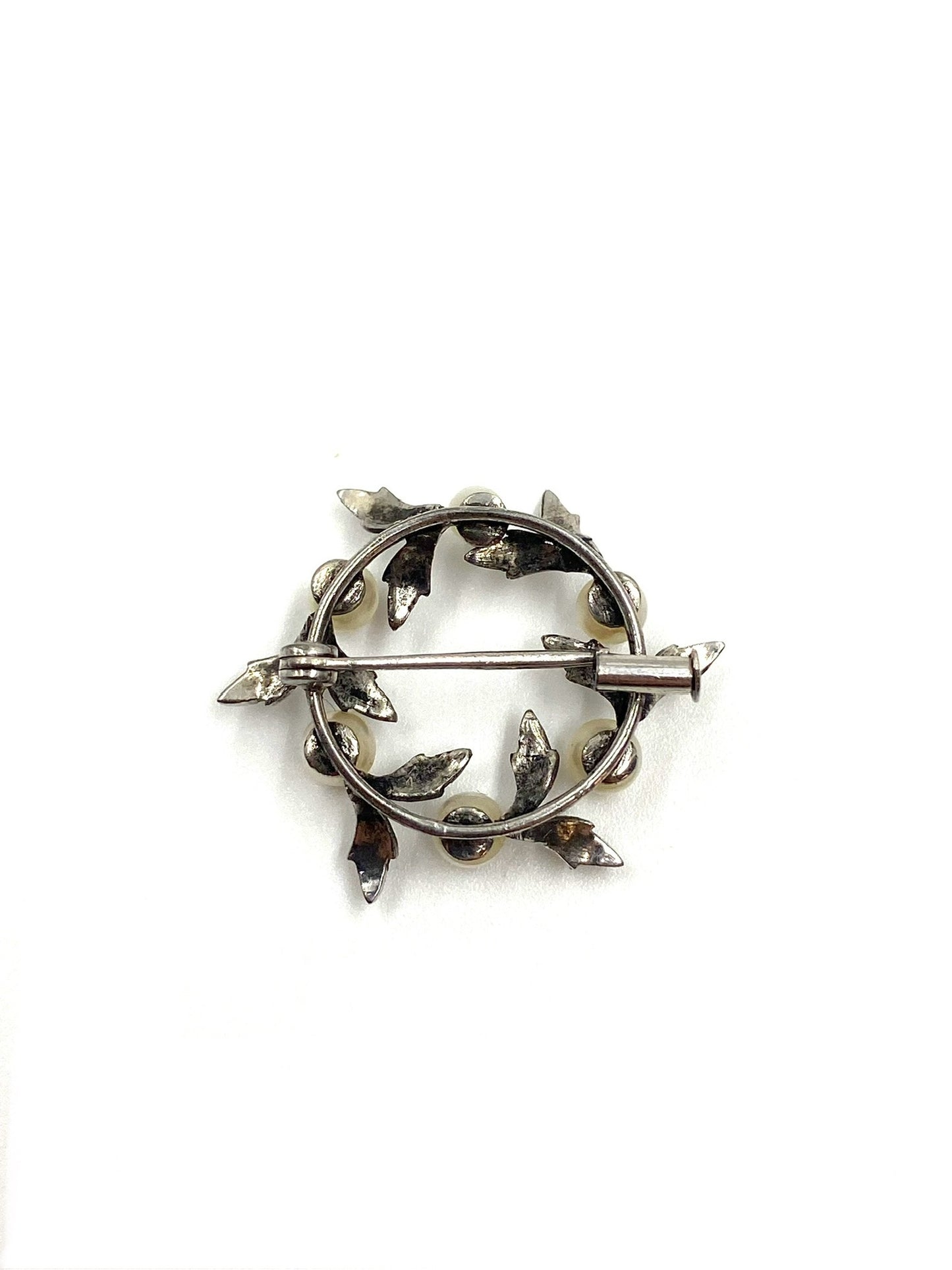 Back of a vintage 1950s sterling silver pearl wreath brooch with a pin closure.