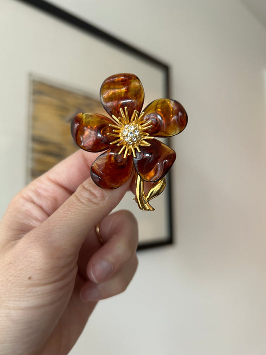 Vintage 1990s Joan Rivers flower brooch with brown lucite petals and gold-toned metal, featuring a rhinestone center.