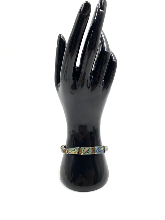 Sterling silver abalone bracelet with iridescent rectangular stones displayed on a black mannequin hand.