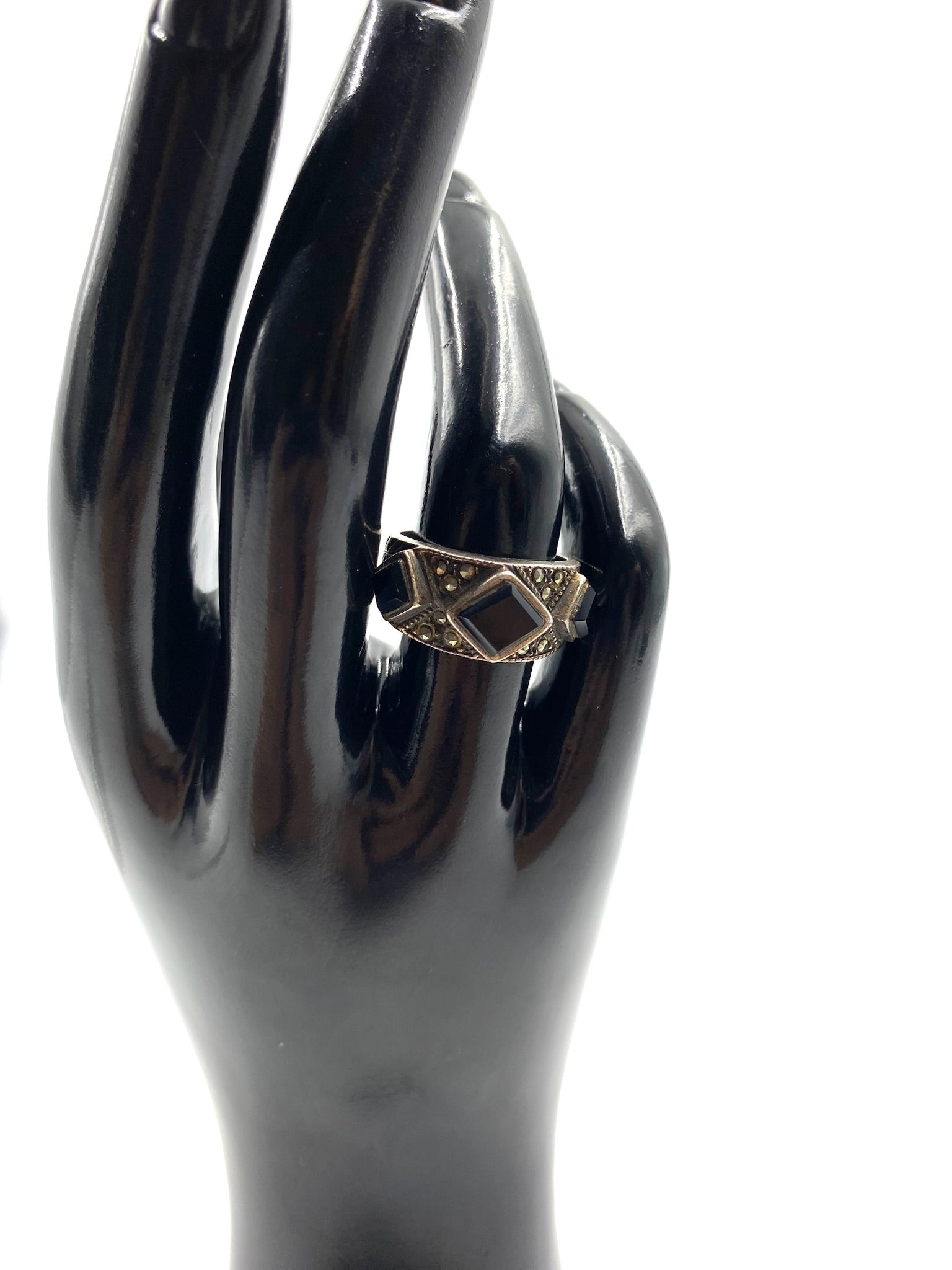 Sterling silver ring size 7 with a square black onyx stone and marcasite accents on a black display hand.