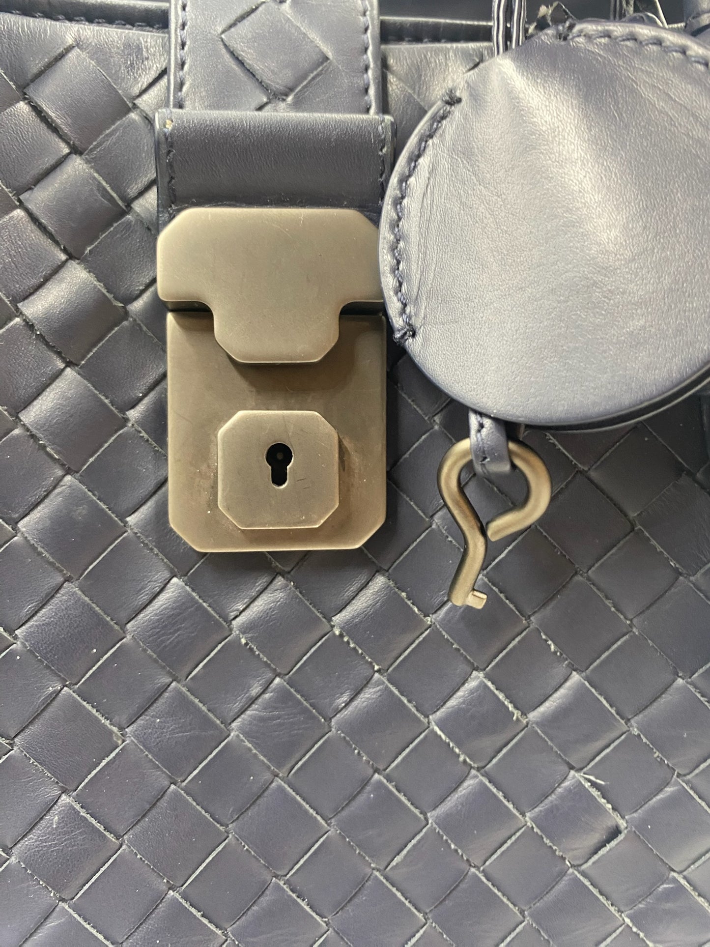 Close-up of Bottega Veneta blue Intrecciato leather Roma bag with gunmetal padlock and key clochette.