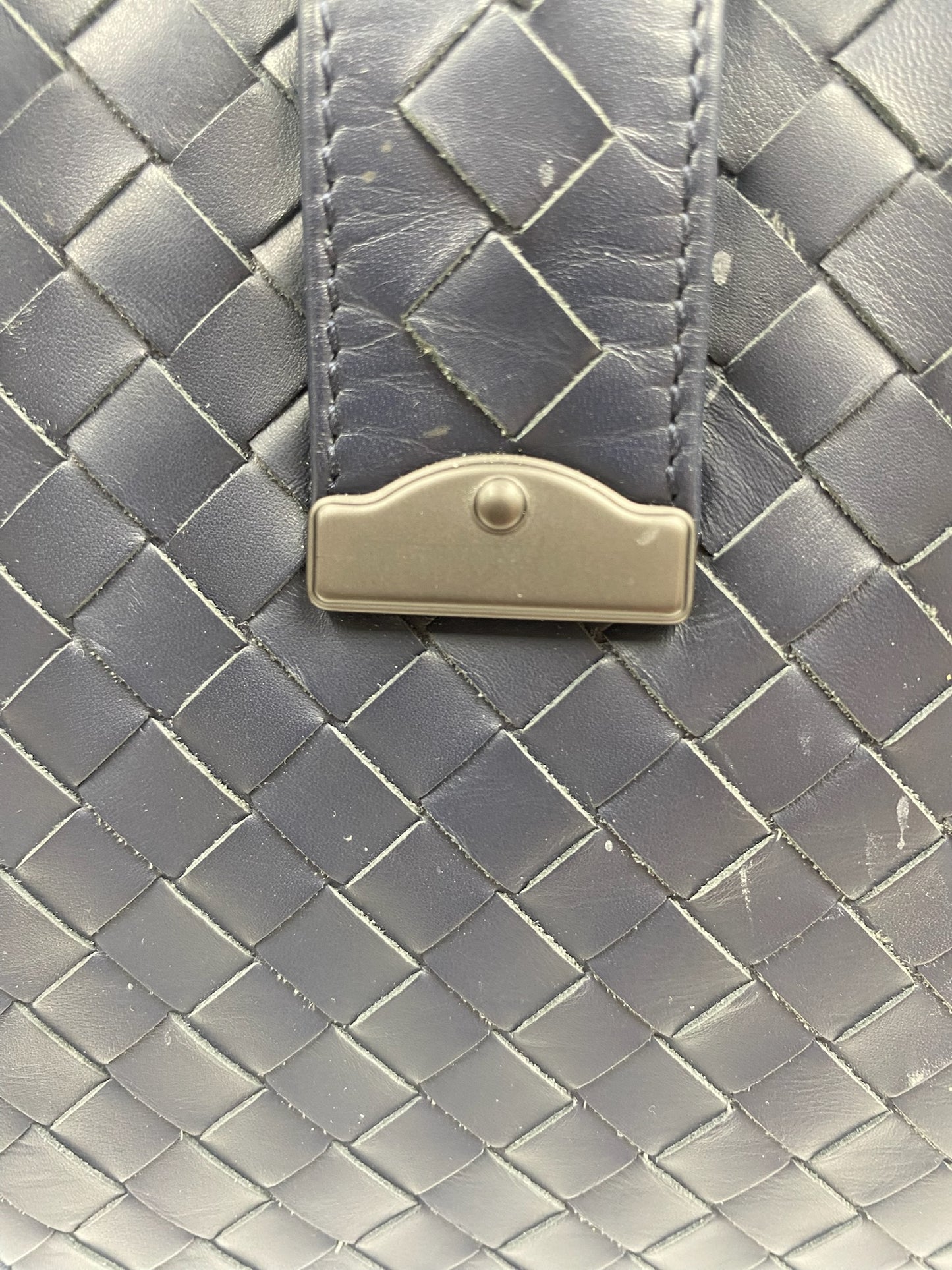 Close-up of Bottega Veneta blue Intrecciato leather with gunmetal hardware closure.