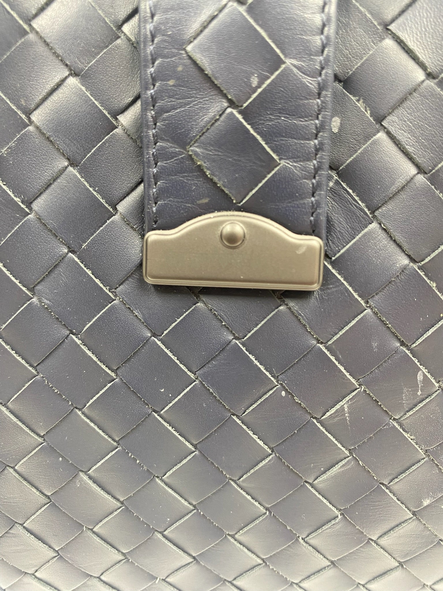 Close-up of Bottega Veneta blue Intrecciato leather with gunmetal hardware closure.
