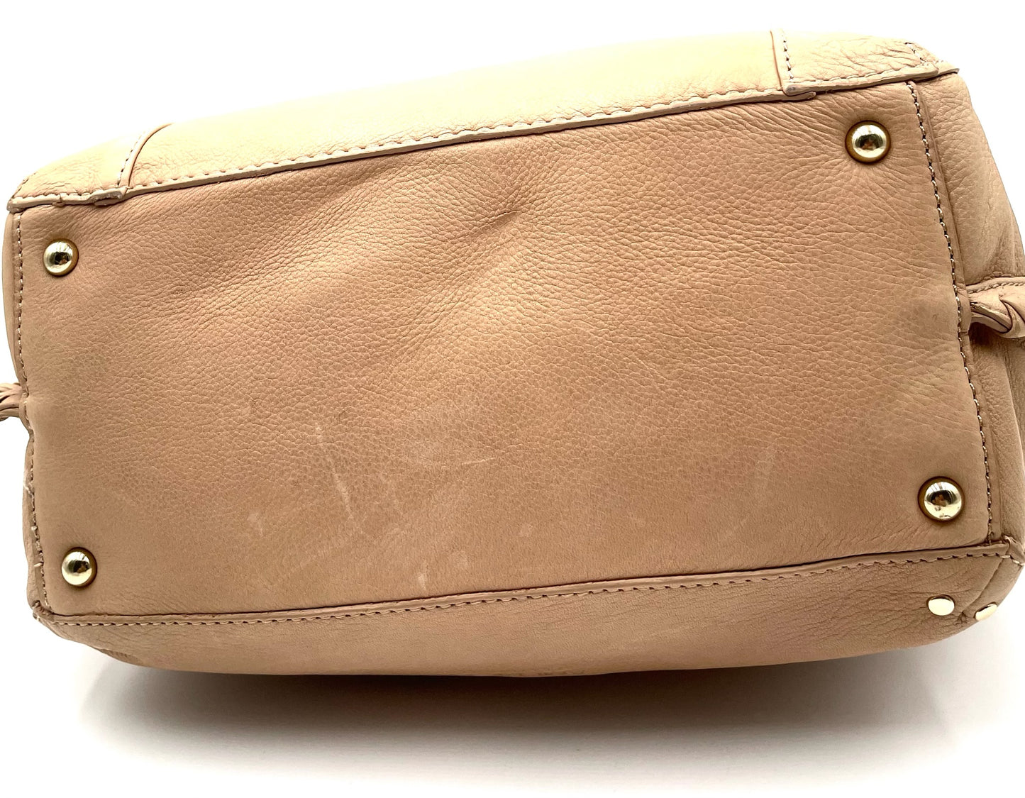 Bottom view of a biege leather American Co shoulder bag with gold-tone hardware feet.