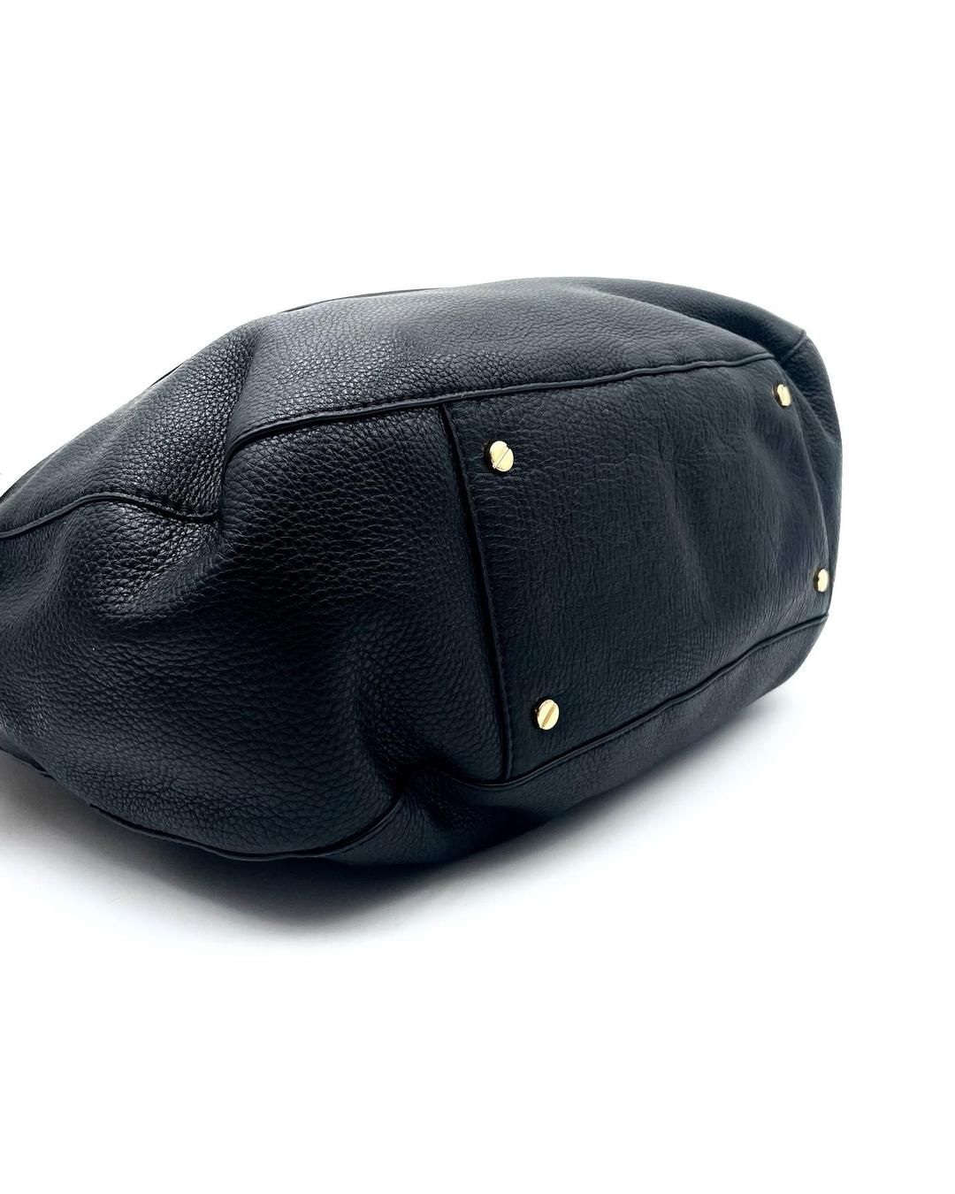 Bottom view of a black pebbled leather Tory Burch Amanda hobo bag with gold-tone protective feet.