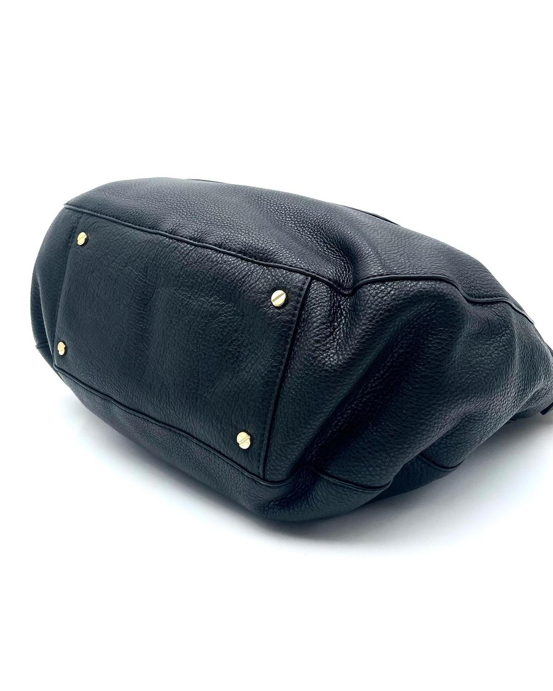 Bottom view of a black pebbled leather Tory Burch Amanda hobo bag with four protective gold-tone metal feet.