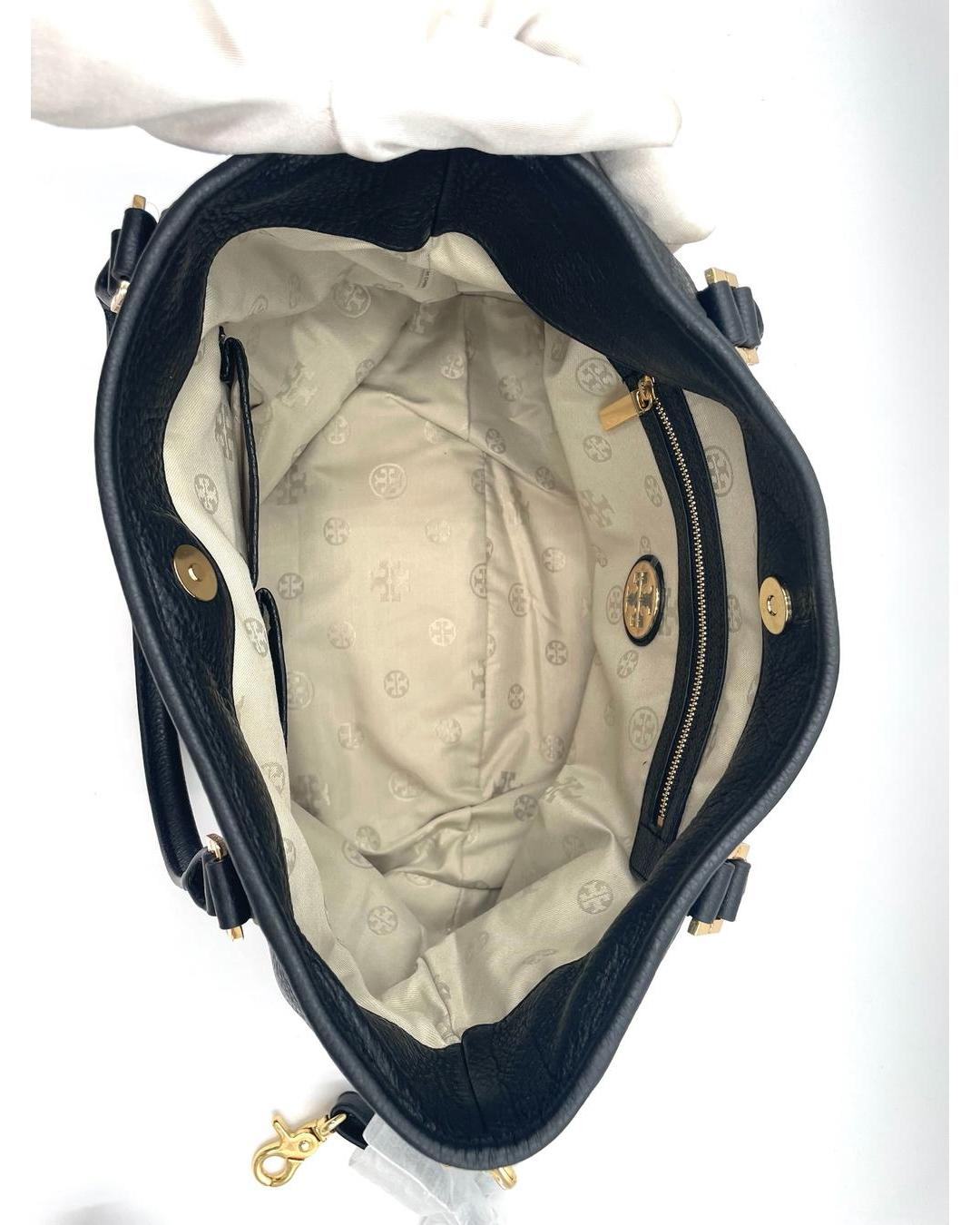 Interior view of a black pebbled leather Tory Burch Amanda hobo bag with a beige logo-print lining and gold-tone hardware.