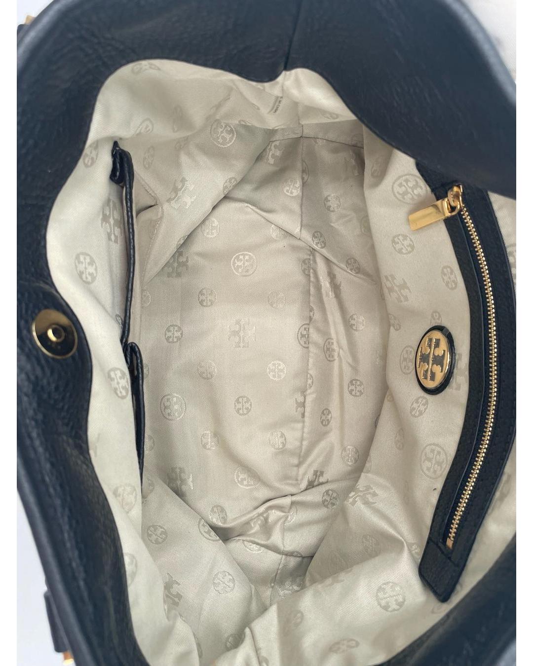 Interior of a black Tory Burch Amanda hobo bag with beige logo-print lining, gold zipper, and signature Double T logo patch.