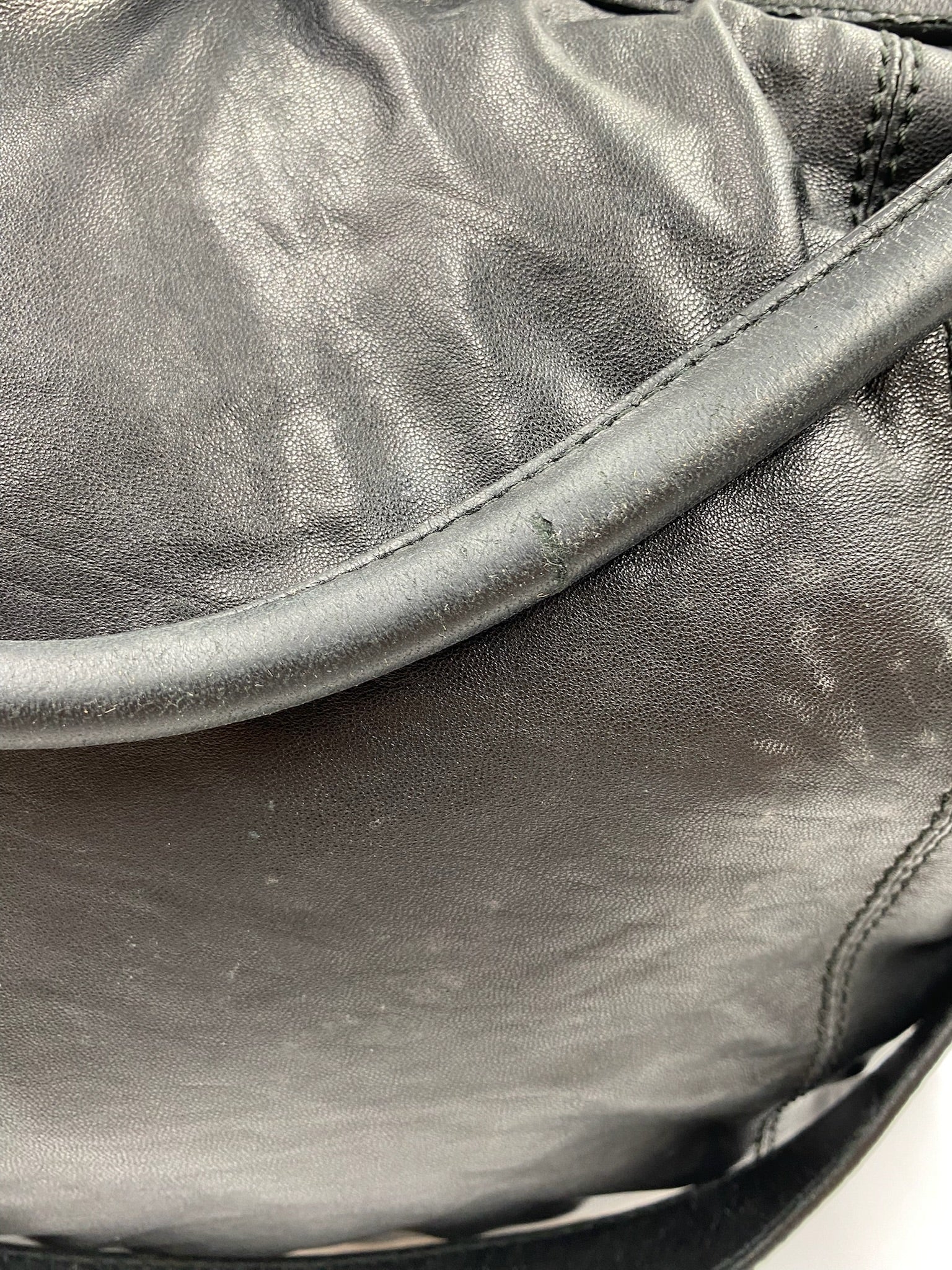 Close-up of a used Burberry Black Large Leather Handbag showing handle wear and textured leather.