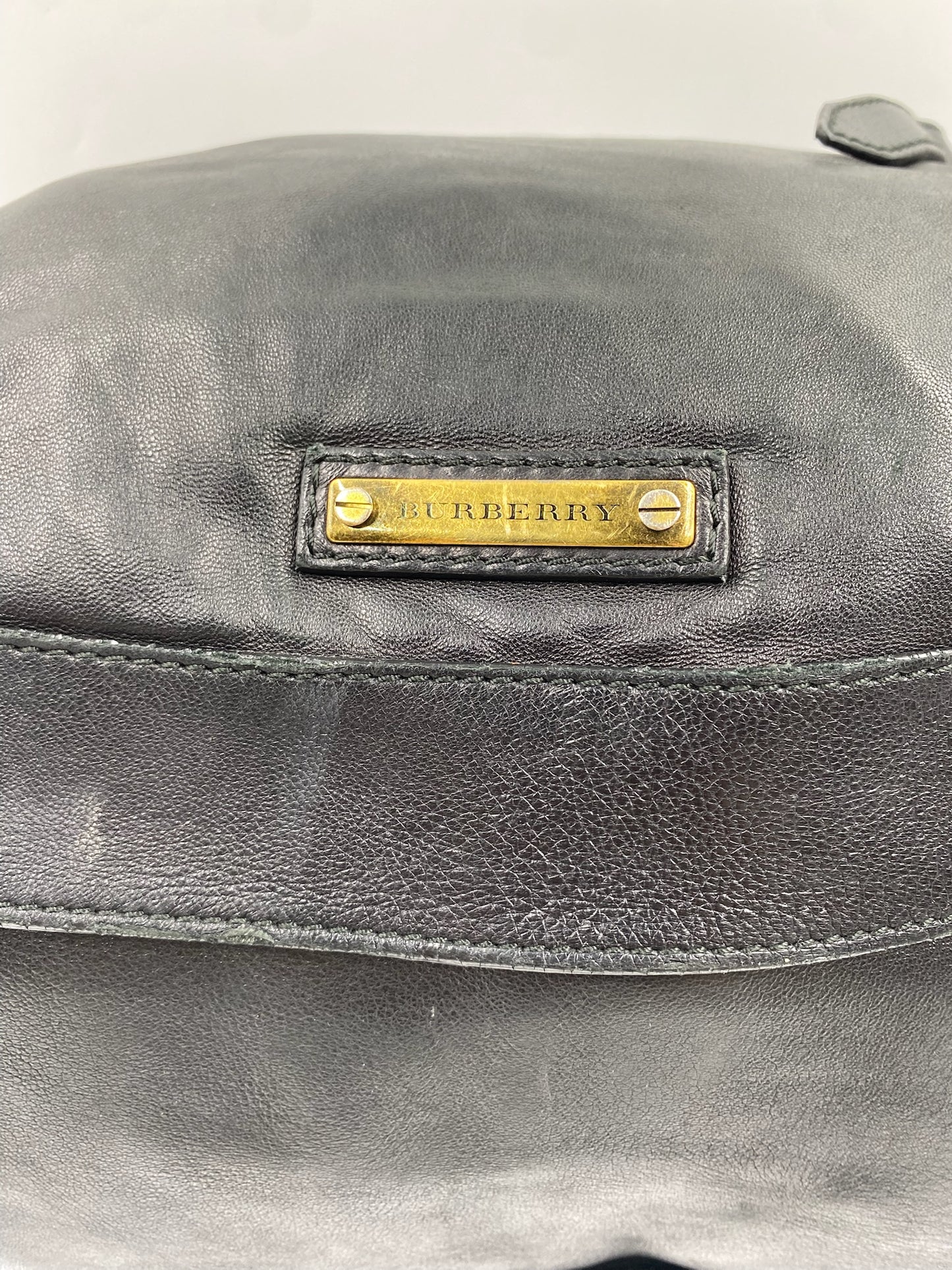 Close-up of a black leather Burberry handbag with a gold "BURBERRY" plaque.