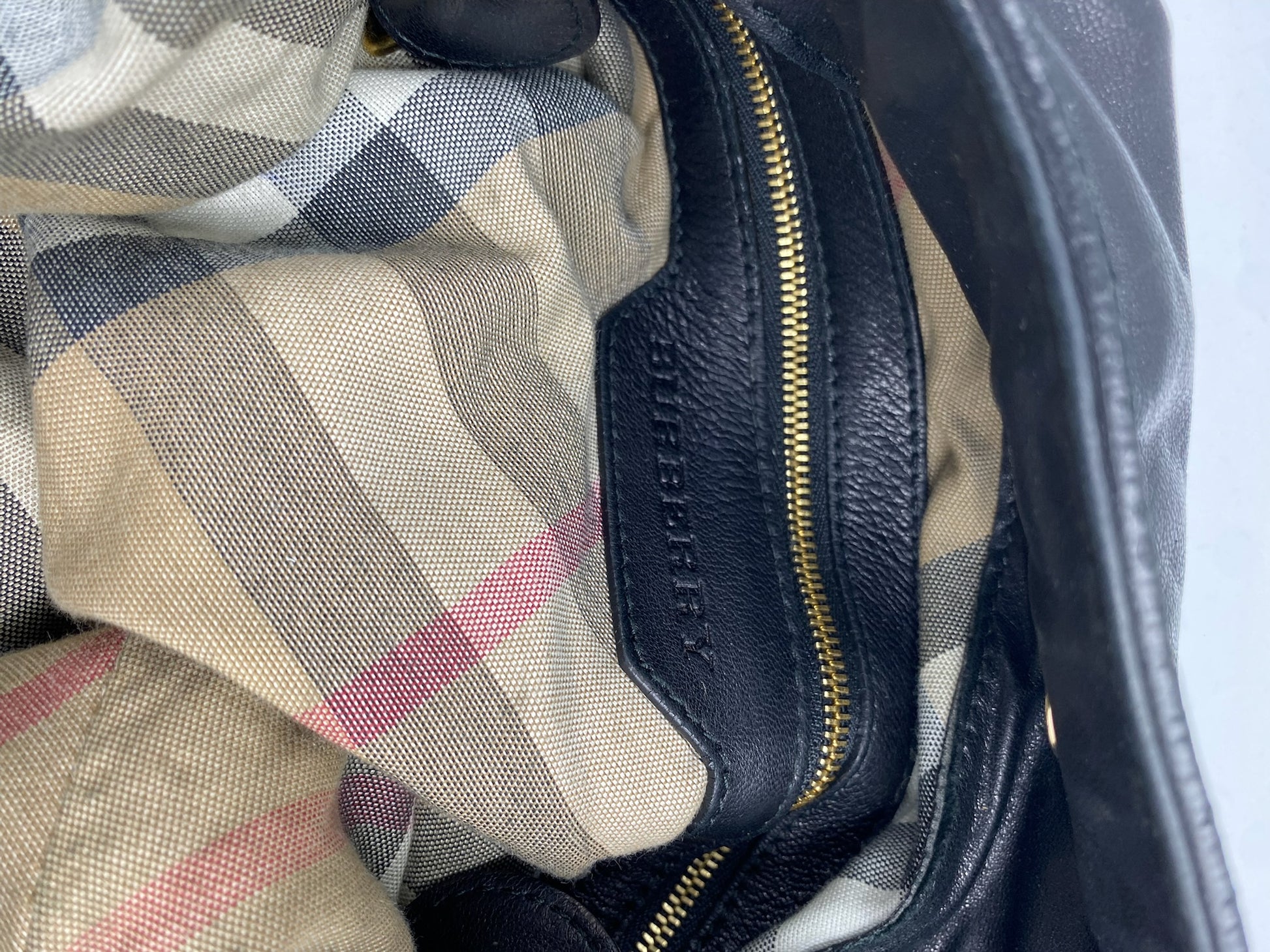 Burberry Black Large Leather Handbag interior with classic checked lining, gold zipper, and leather logo.
