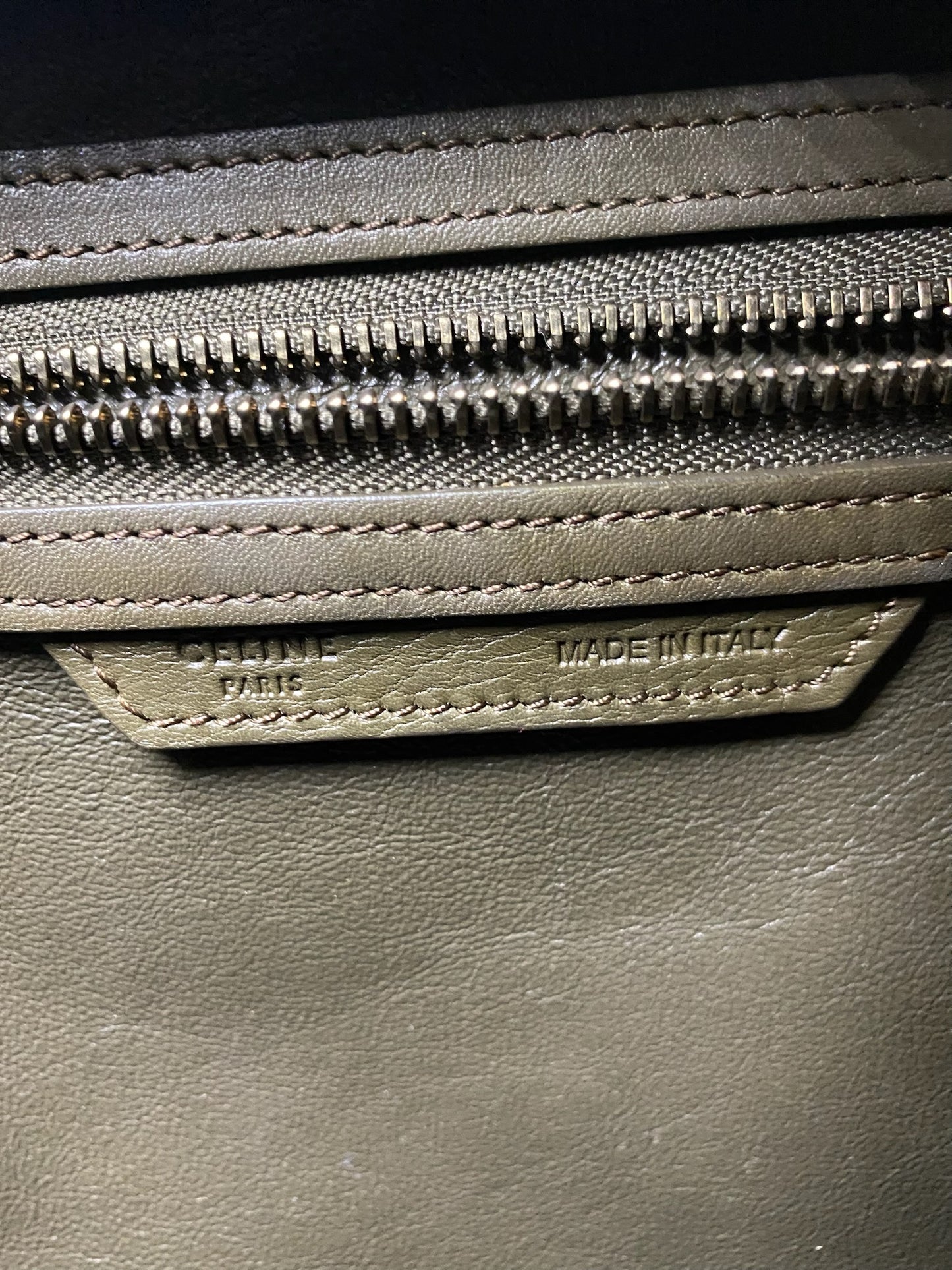 Close-up of Celine Olive Calfskin Micro Luggage Tote's "Made in Italy" stamp and gold-tone zipper.
