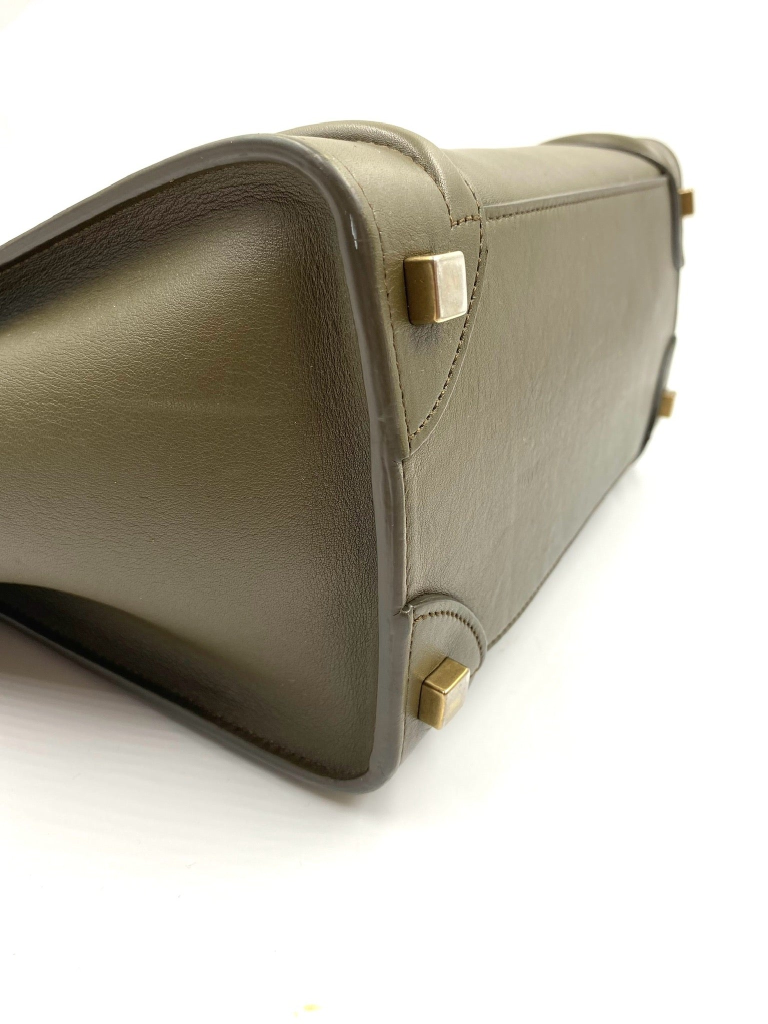 Celine Olive Calfskin Micro Luggage Tote, showing its side profile, gold-tone hardware, and protective feet.