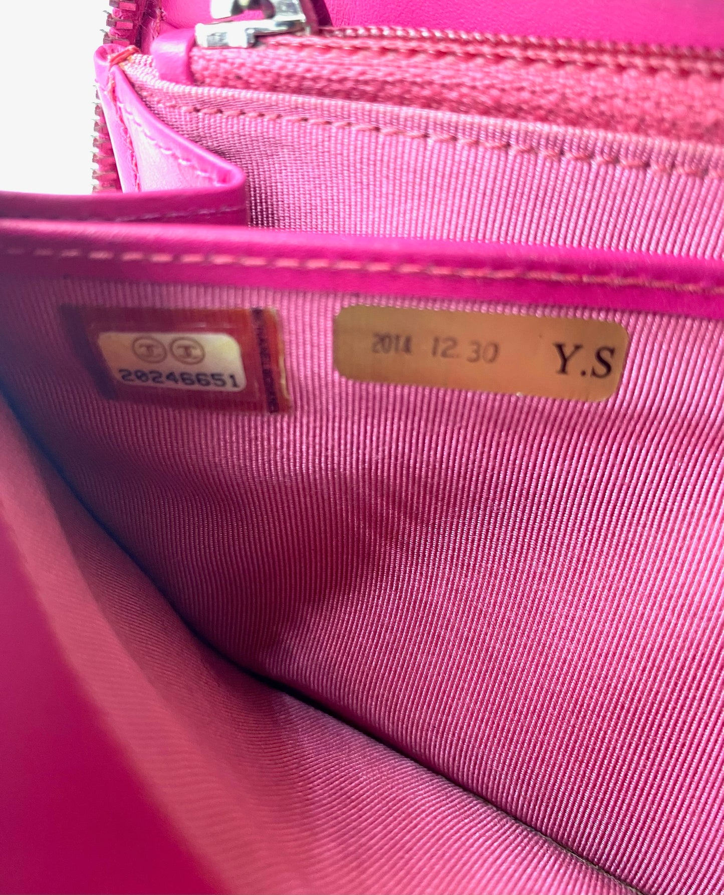 Close-up of the interior of a pink Chanel caviar zip wallet, showing authenticity serial number and date.