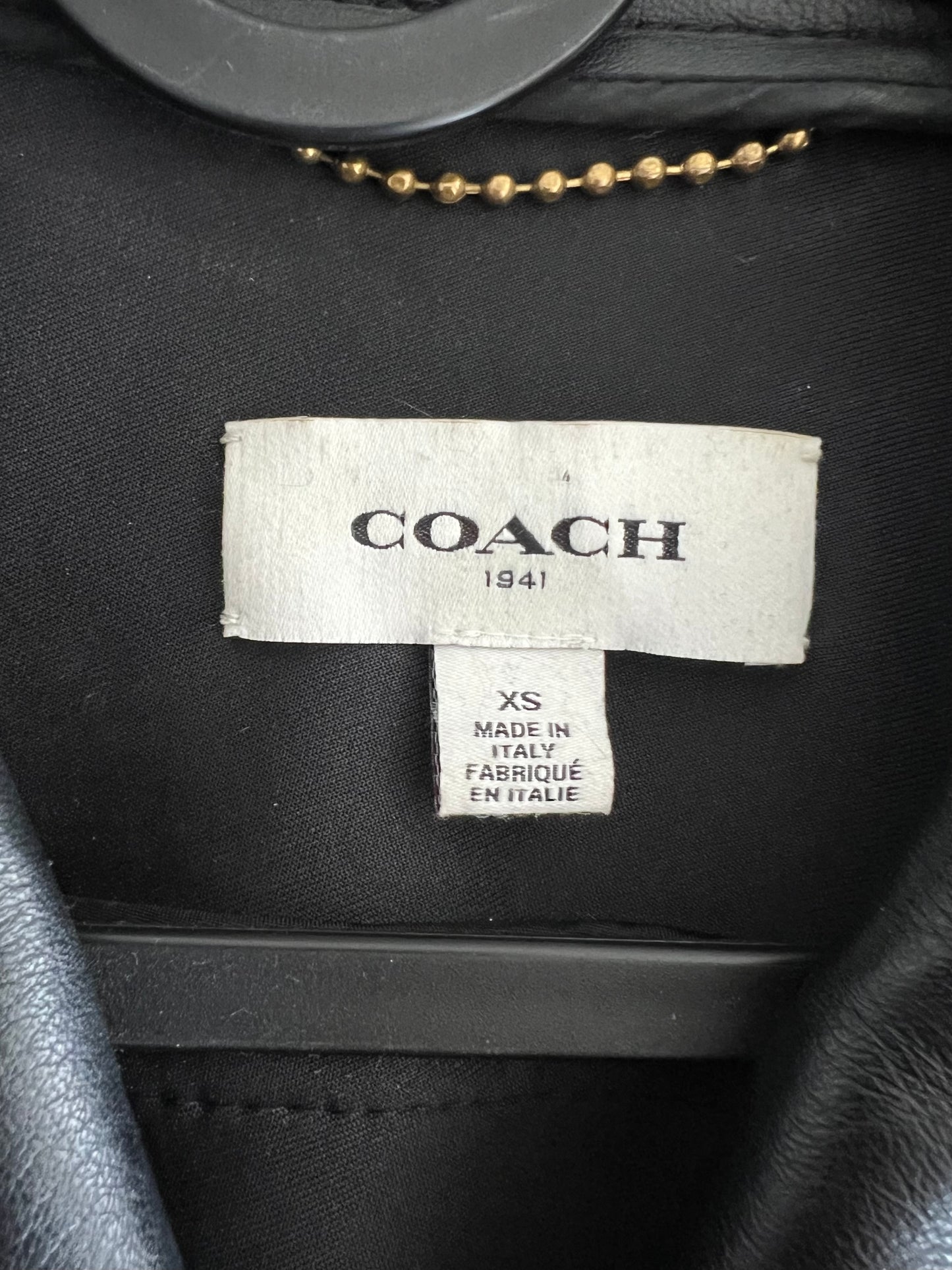 Close-up of Coach 1941 black leather biker vest label, size XS, Made in Italy.