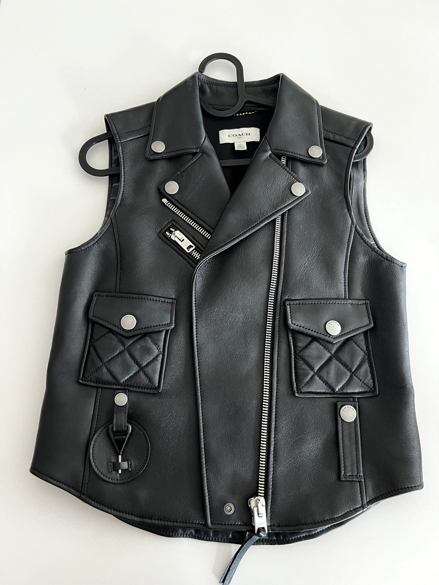 Coach 1941 black leather biker vest, size XS, with silver zippers, snap buttons, and quilted pockets.