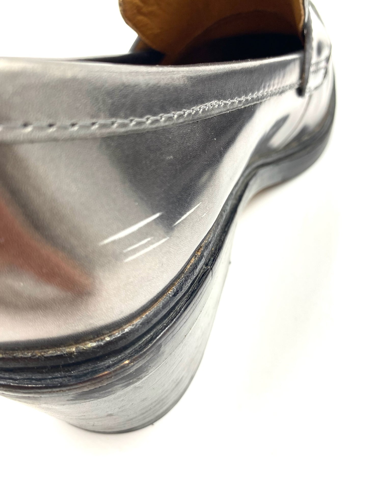 Close-up of the heel of a Coach Grey Metallic Loafer, showing scratches and wear on the metallic leather.