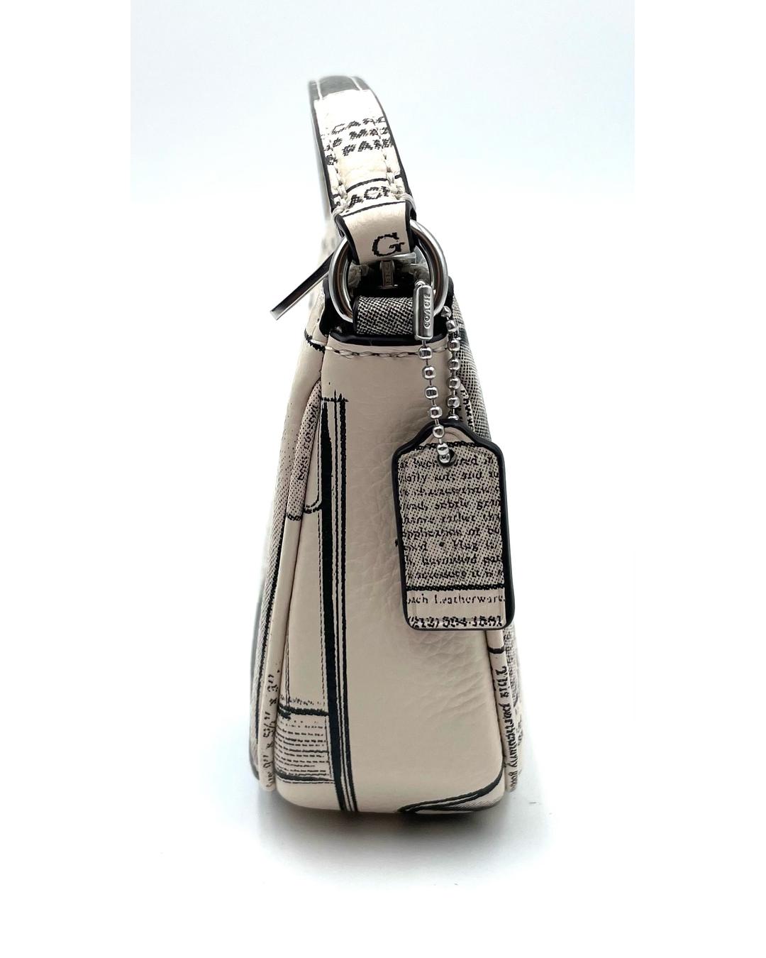 Side view of a Coach Nolita 19 mini bag in white pebble leather with a black newspaper print and matching leather hangtag.
