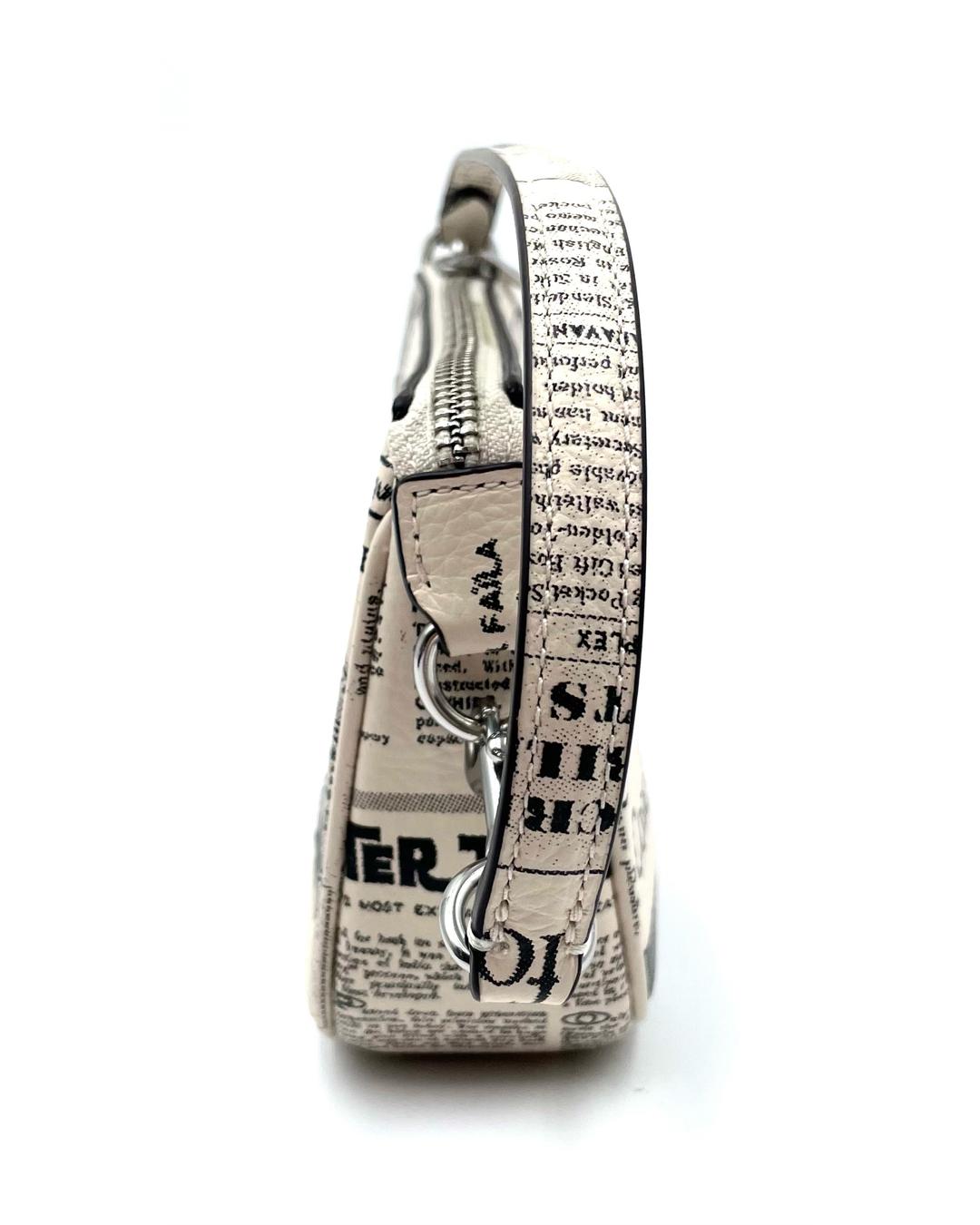 Side view of a Coach Nolita 19 mini bag in cream pebble leather with a black newspaper print and silver hardware.
