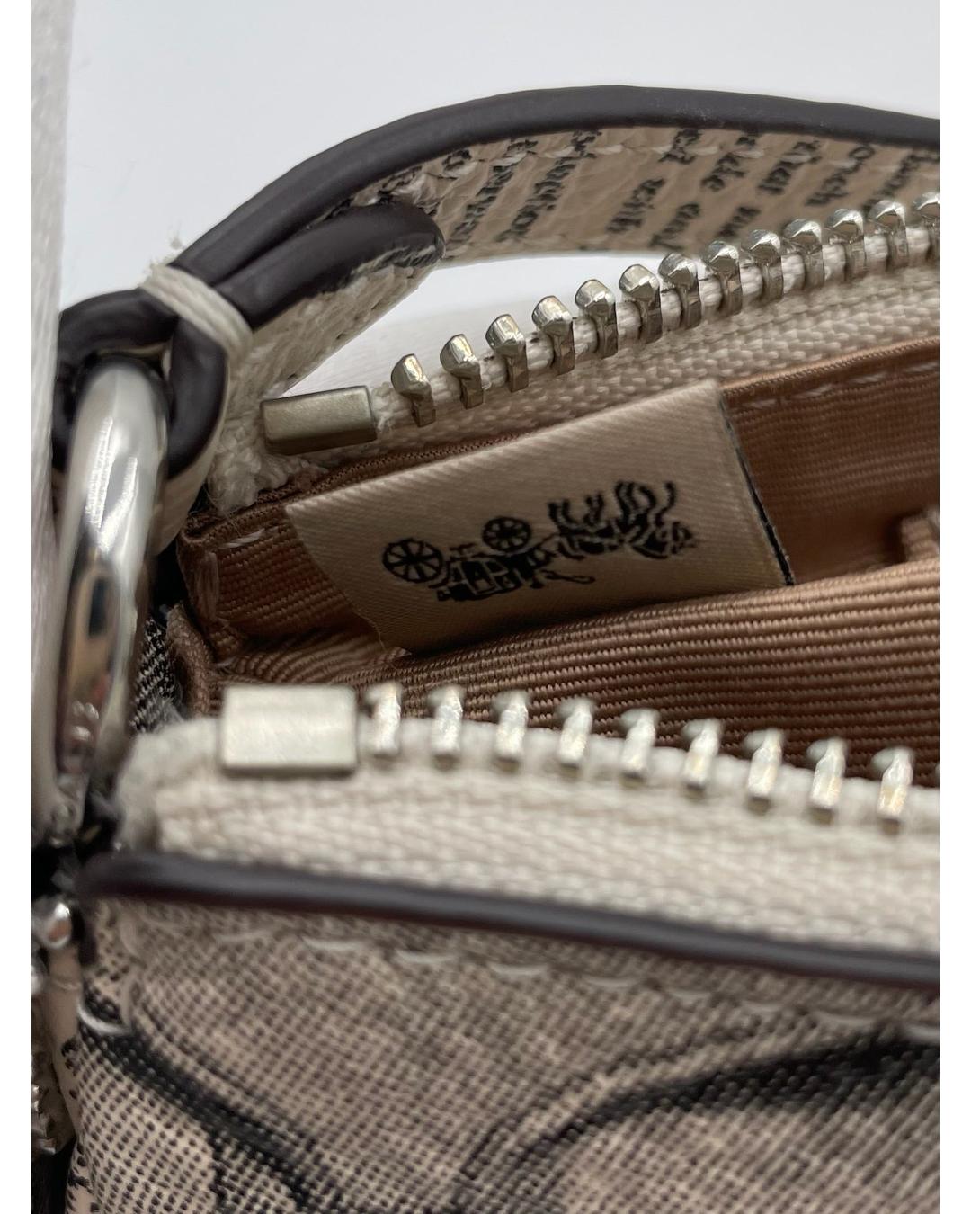 Interior of Coach Nolita 19 bag with newspaper print, silver zipper, and Coach logo fabric tag.