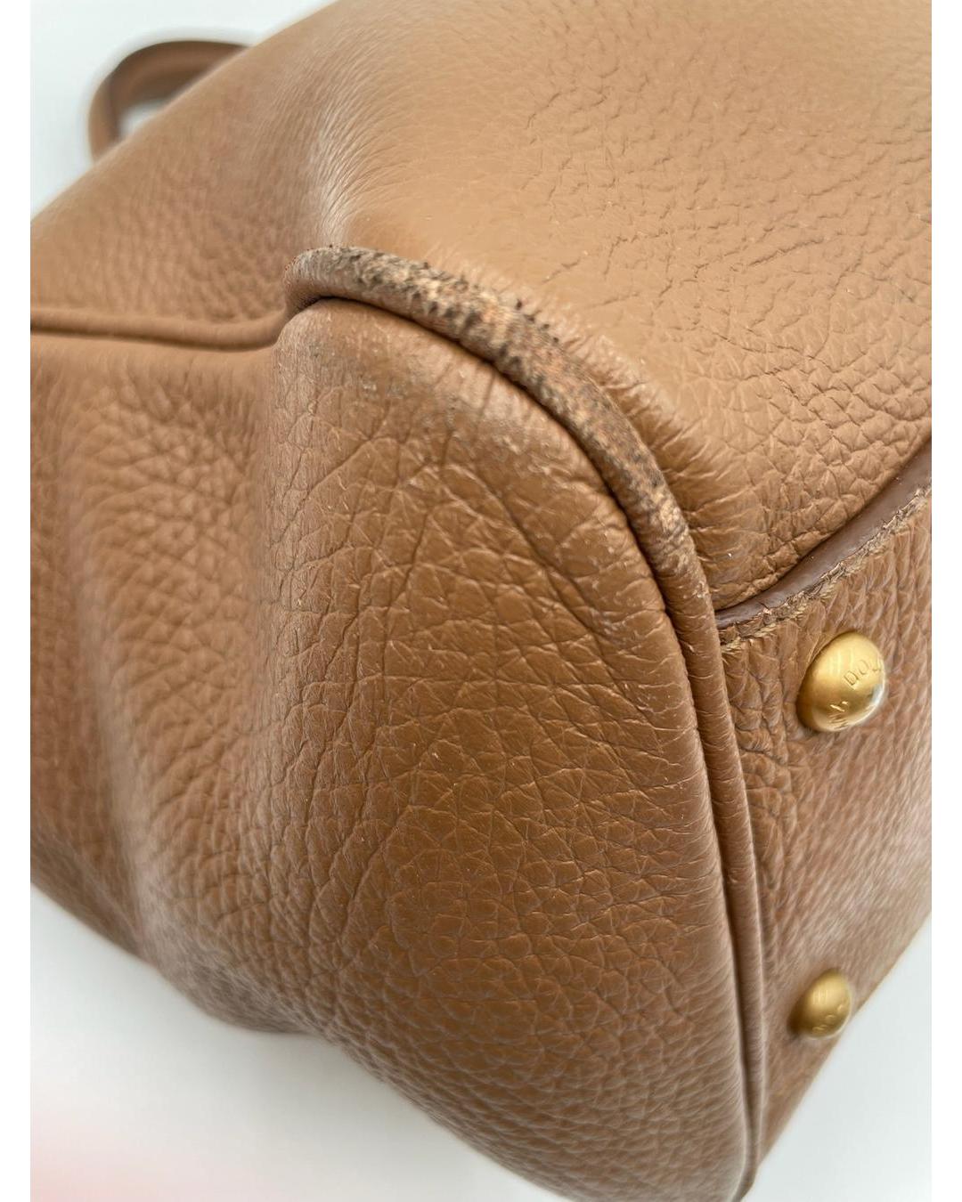 Close-up of a caramel calfskin Dolce & Gabbana Miss Sicily bag showing corner wear and gold-tone metal feet.