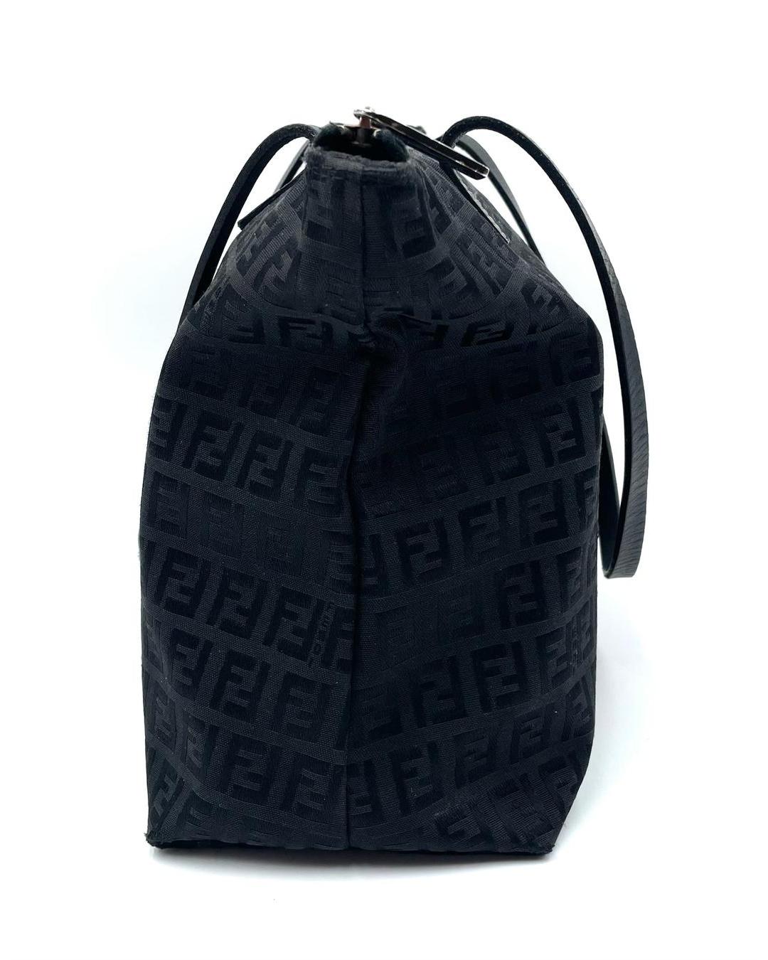 Black Fendi Zucca monogram shoulder tote with a top zip closure and slim leather straps against a white background.