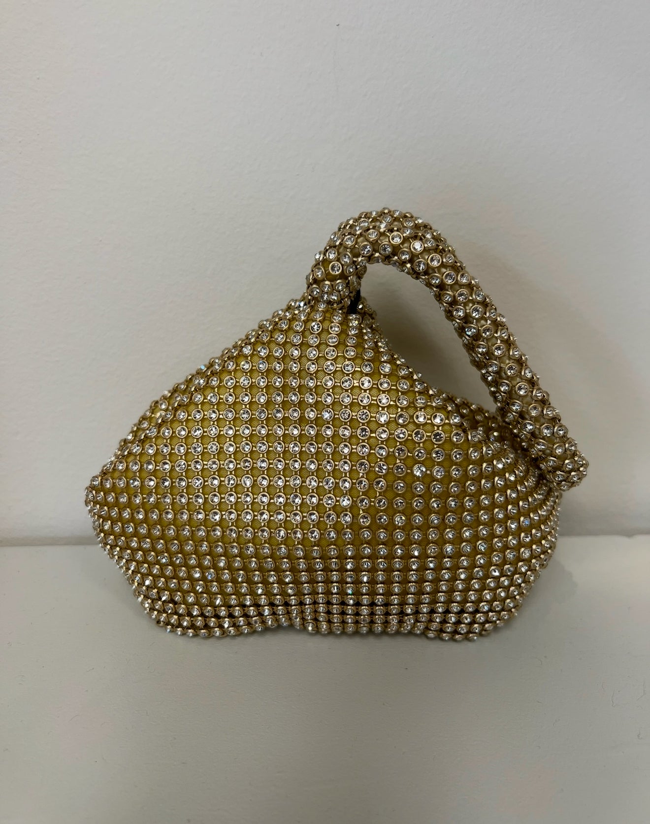 Gold mesh clutch covered in sparkling rhinestones with a structured top handle and unique sculptural shape.