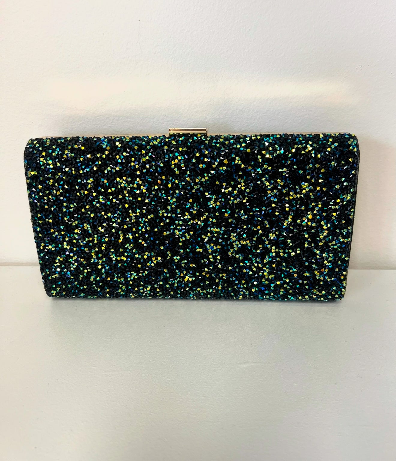 Rectangular evening clutch covered in shimmering green and black glitter with a gold metal frame clasp.