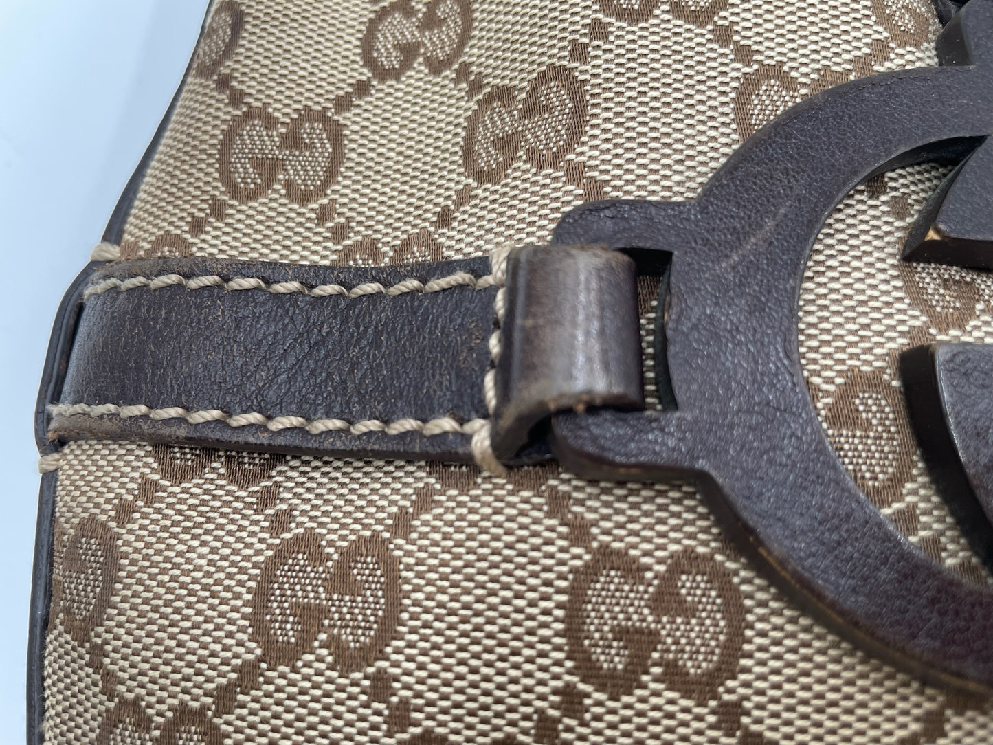 Beige and brown Gucci GG canvas hobo bag with dark brown leather trim and interlocking G logo detail.