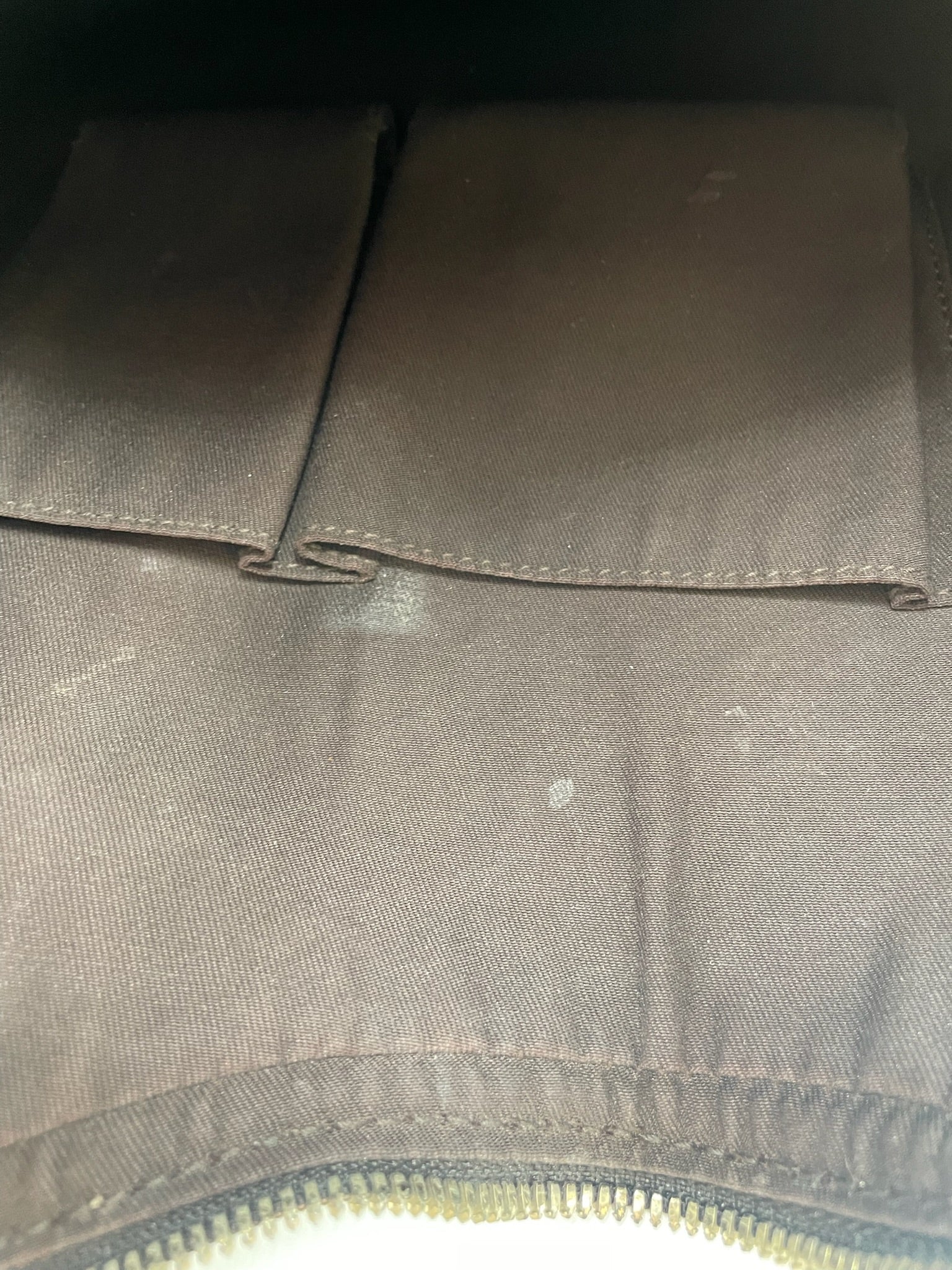 Interior of Gucci hobo bag featuring dark brown fabric lining, slip pockets, and visible light wear marks.