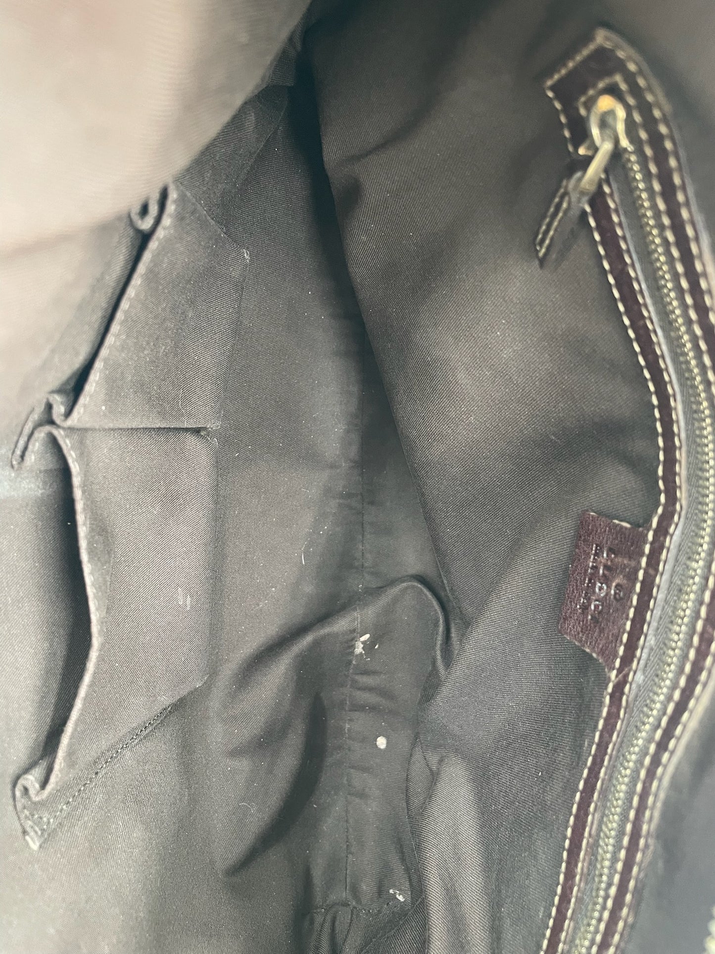 Interior of a Gucci hobo bag featuring dark brown fabric lining, a zippered side pocket, and double slip pockets.