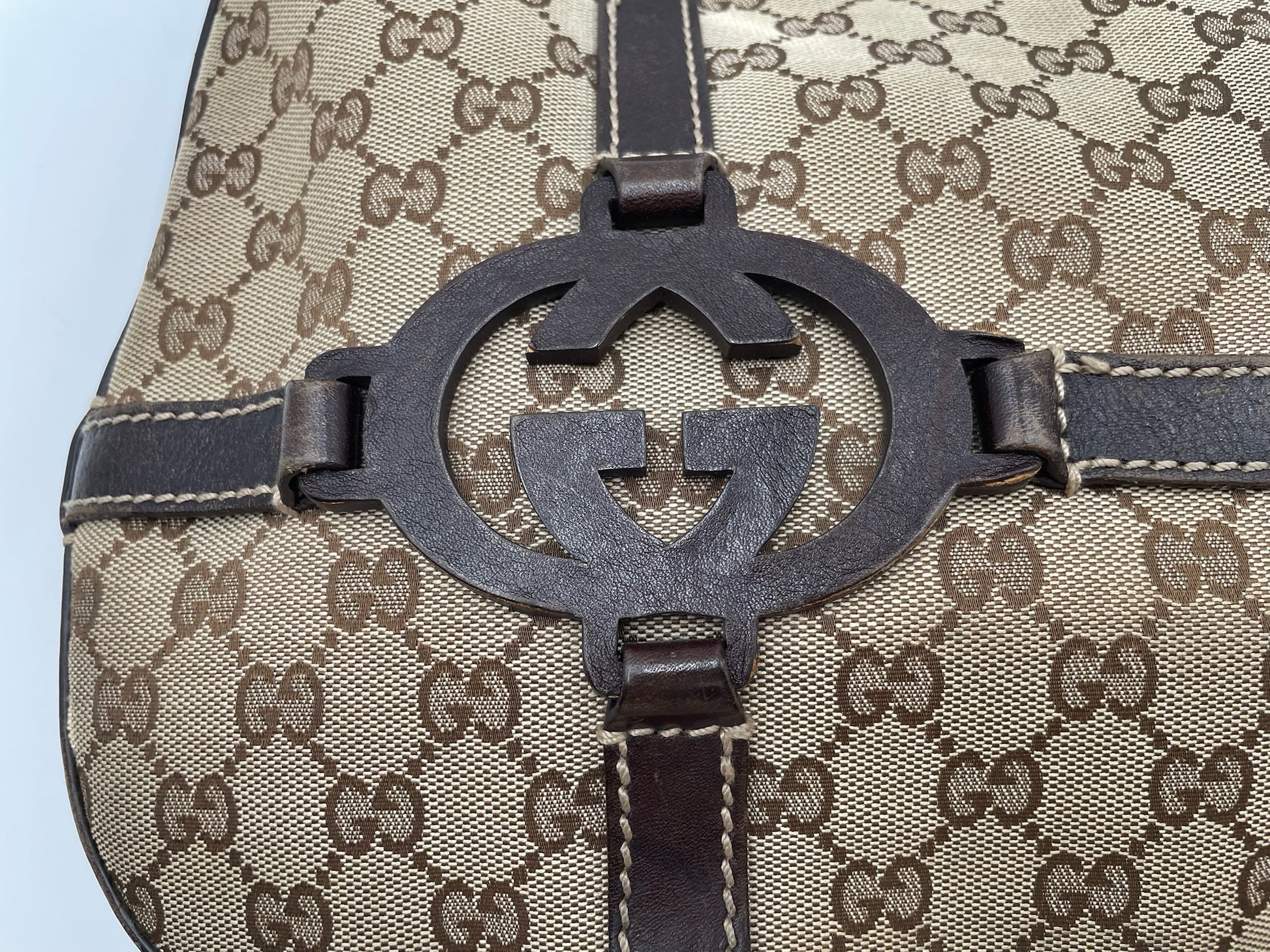 Beige and brown GG canvas Gucci hobo bag featuring a prominent dark brown leather interlocking G logo detail.