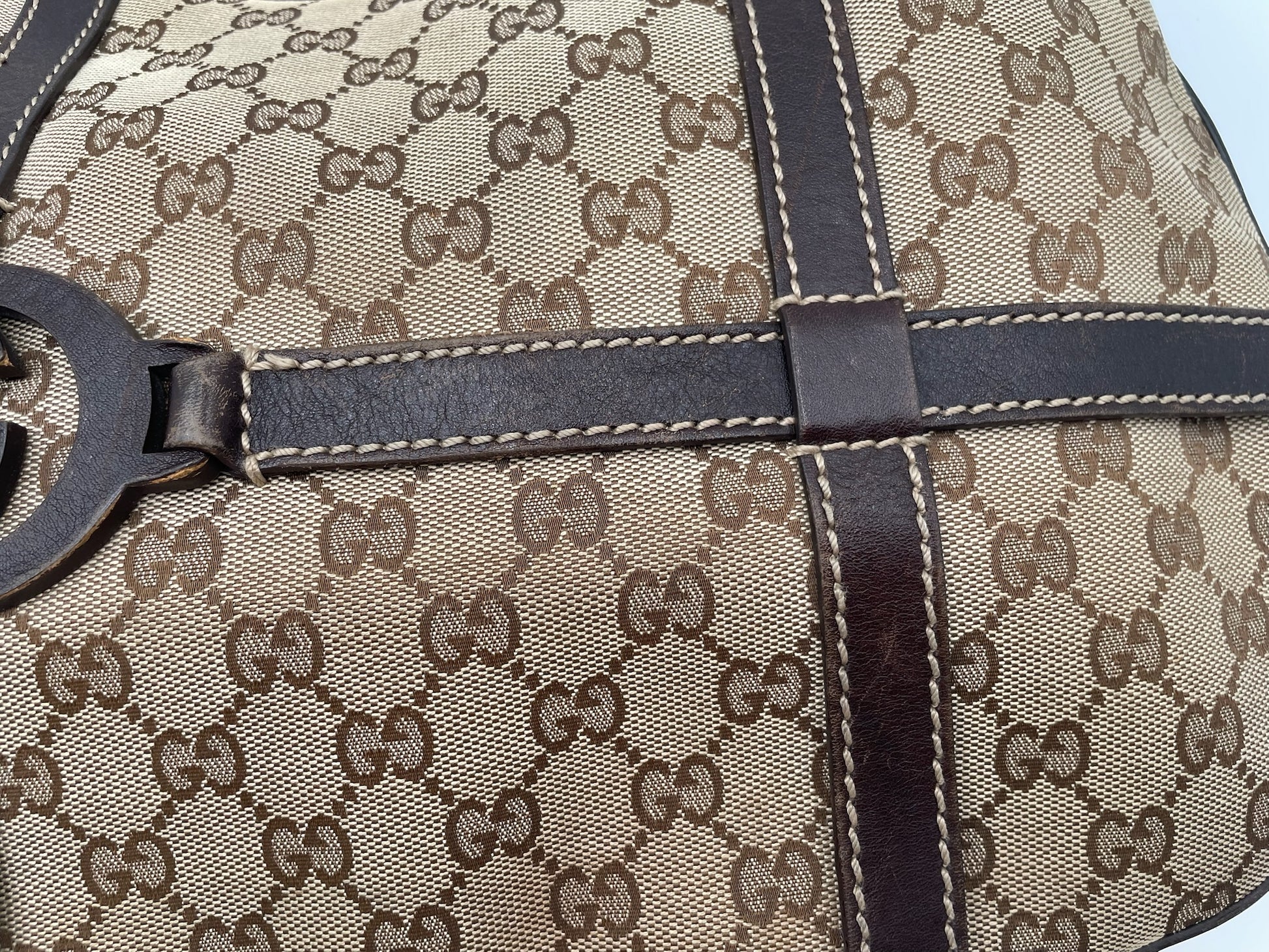 Beige and brown GG canvas Gucci hobo bag with dark brown leather trim and interlocking G logo detail.