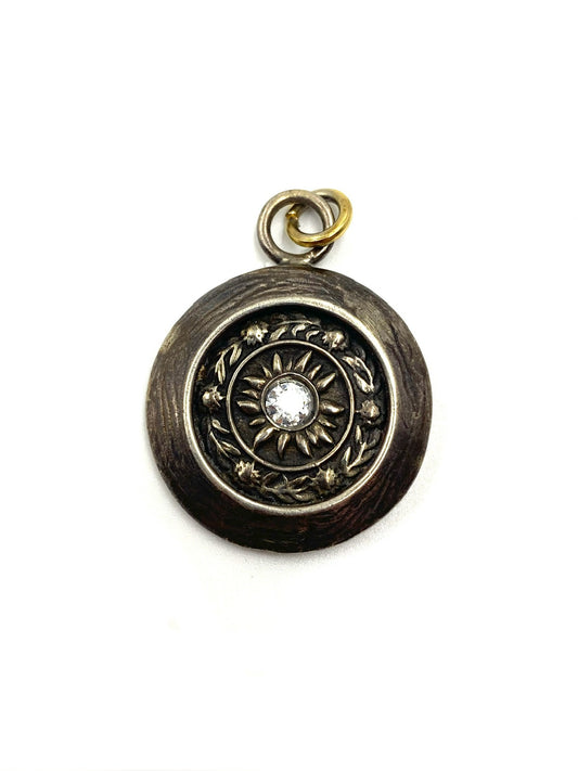 Karyn Chopik bronze round starburst pendant with rhinestone center and gold accent ring.