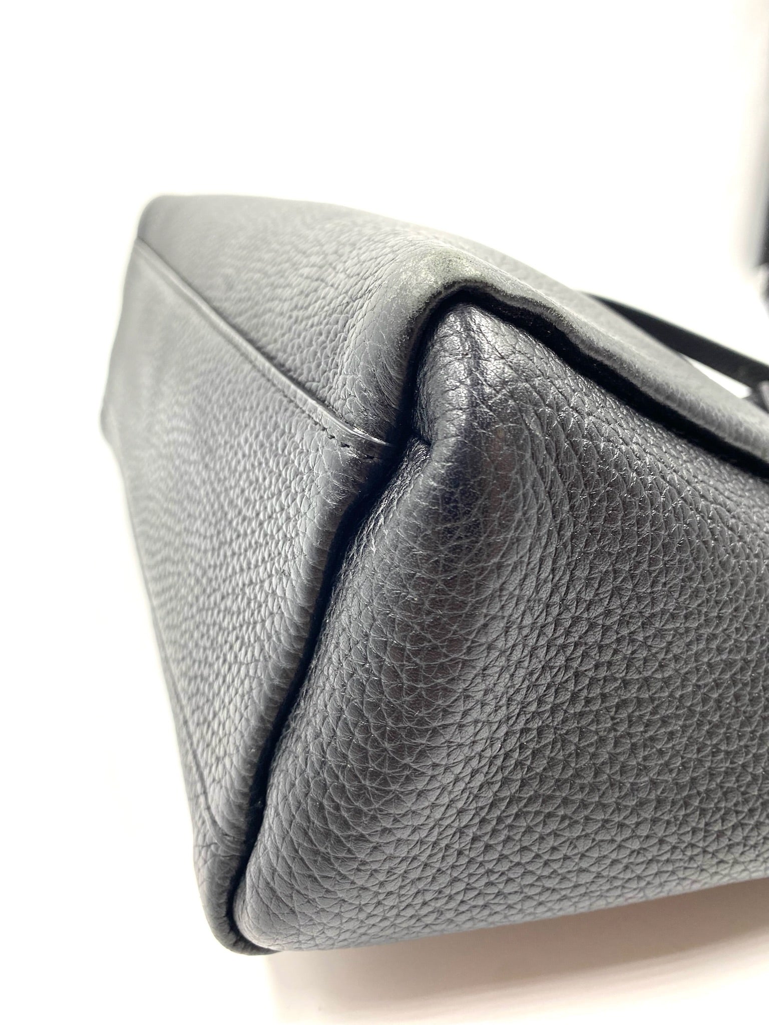 Kate Spade black pebbled leather tote bag, showing the side and bottom corner with visible stitching.