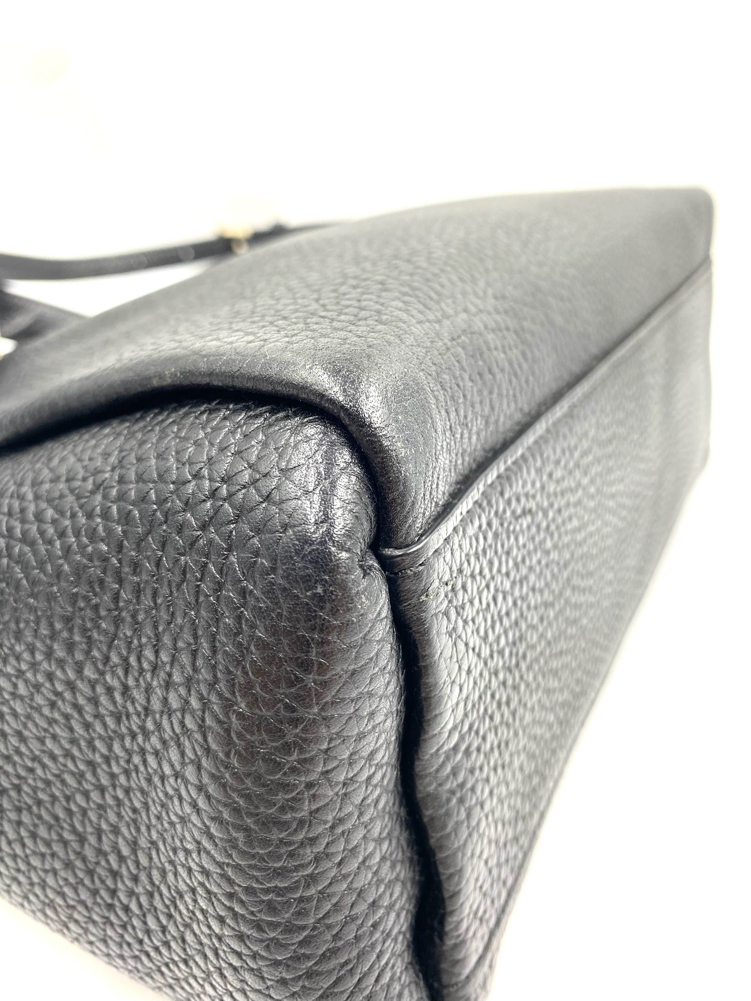 Kate Spade black pebbled leather tote bag, showing the side and top with a subtle gold accent.