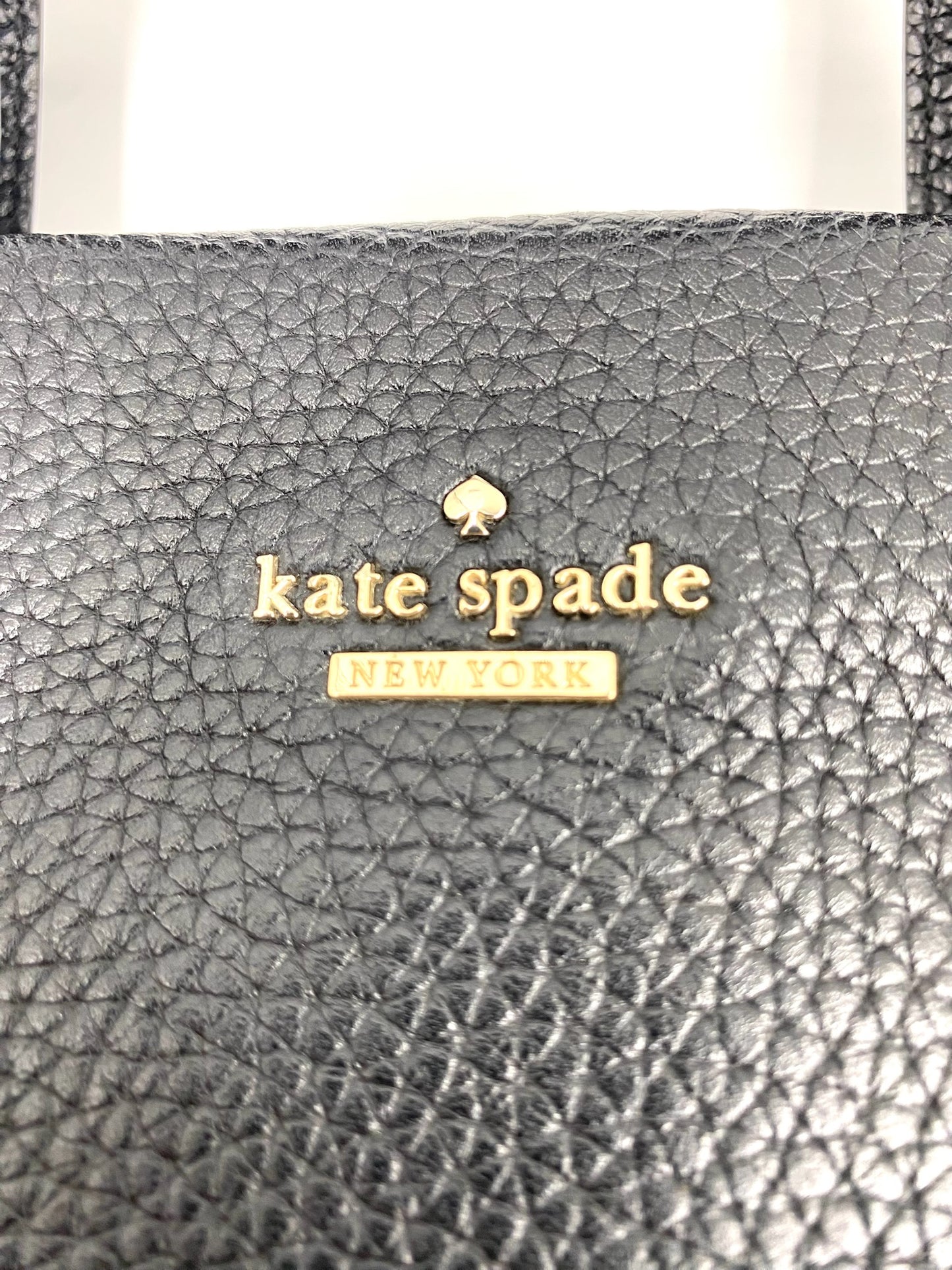 Close-up of a black pebbled leather Kate Spade New York tote bag with gold logo.