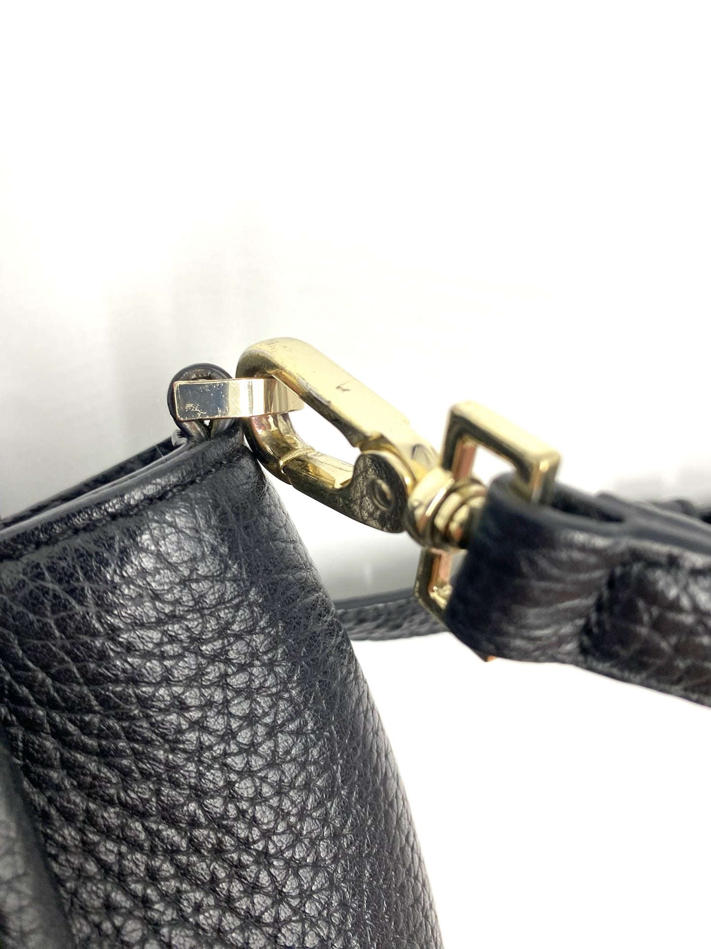 Close-up of a Kate Spade black pebbled leather tote with a gold-tone detachable strap clasp.