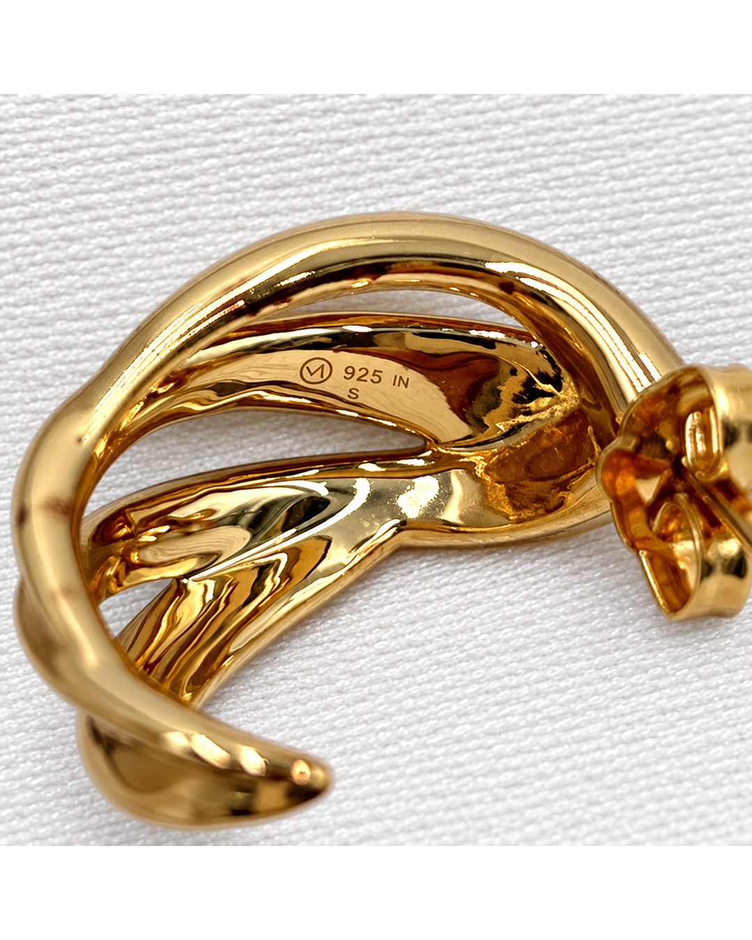 Mejuri curved gold dome earring with a polished finish, featuring a 925 sterling silver hallmark on a white fabric background.