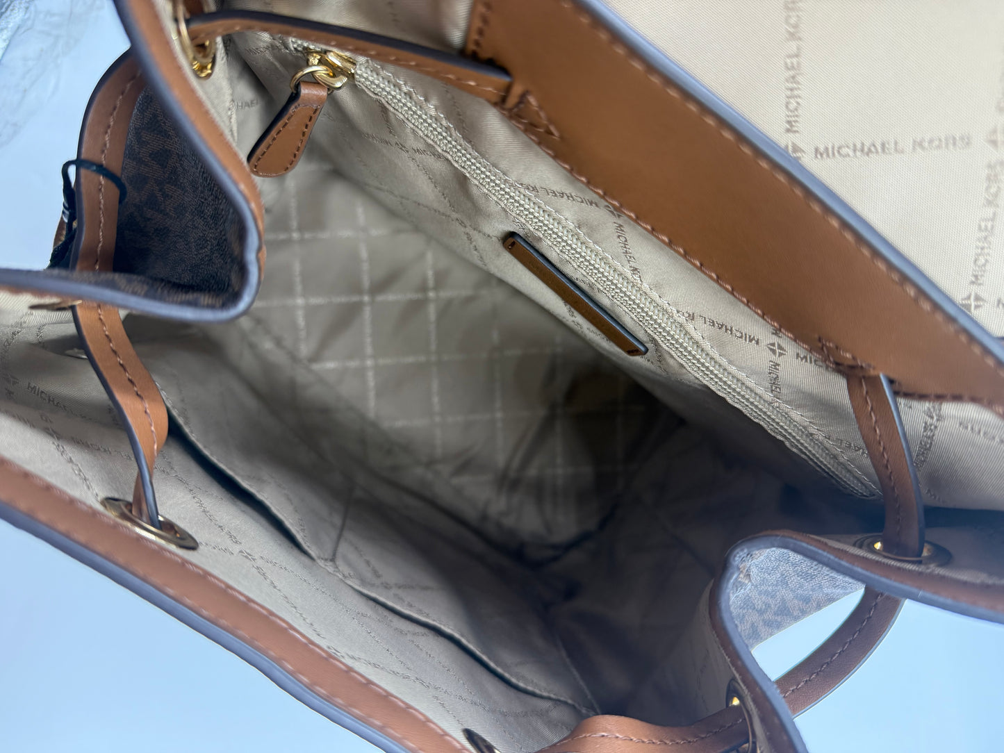 Michael Kors large logo Jet Set backpack interior, showing beige lining, zip pocket, and slip pockets.