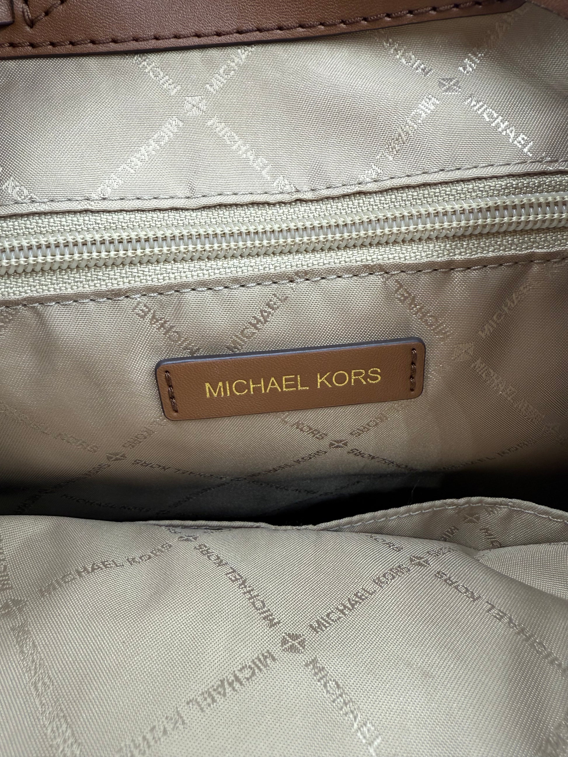 Michael Kors Large Logo Jet Set Backpack interior with beige lining, zip pocket, and brown leather logo tag.