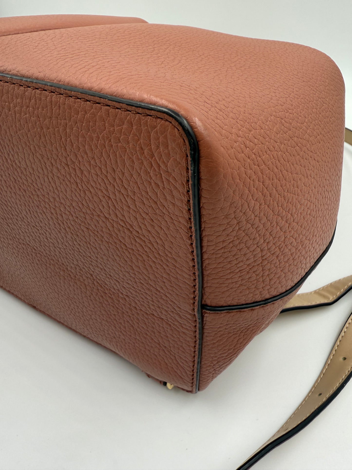 Michael Kors Peach Bedford large leather convertible backpack, close-up of textured base and side.