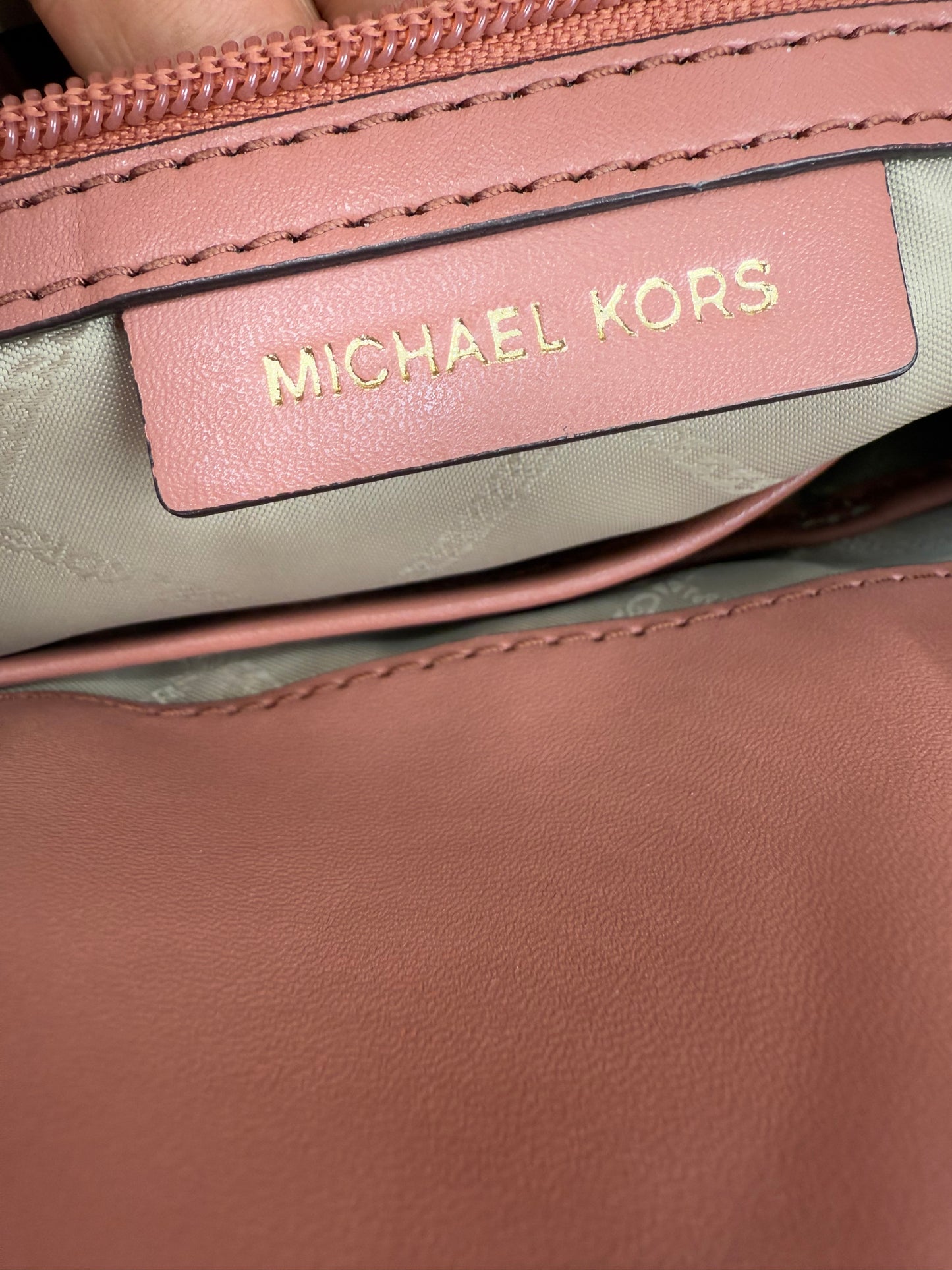 Close-up of Michael Kors Peach Bedford large leather convertible backpack interior with gold logo.