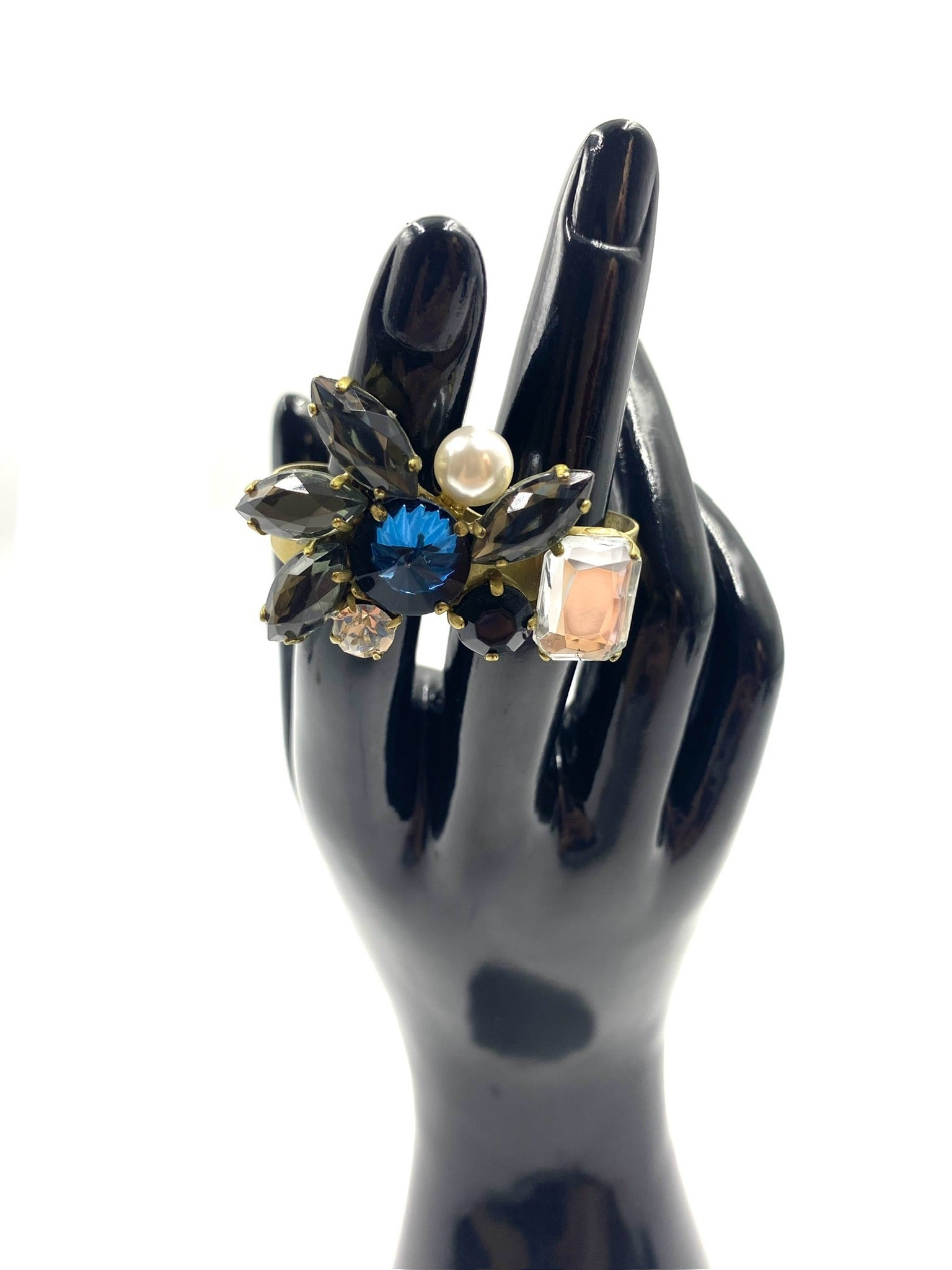 Multicolor rhinestone double finger adjustable ring with black, blue, pink, and clear gems, and a pearl, on a gold-tone band.